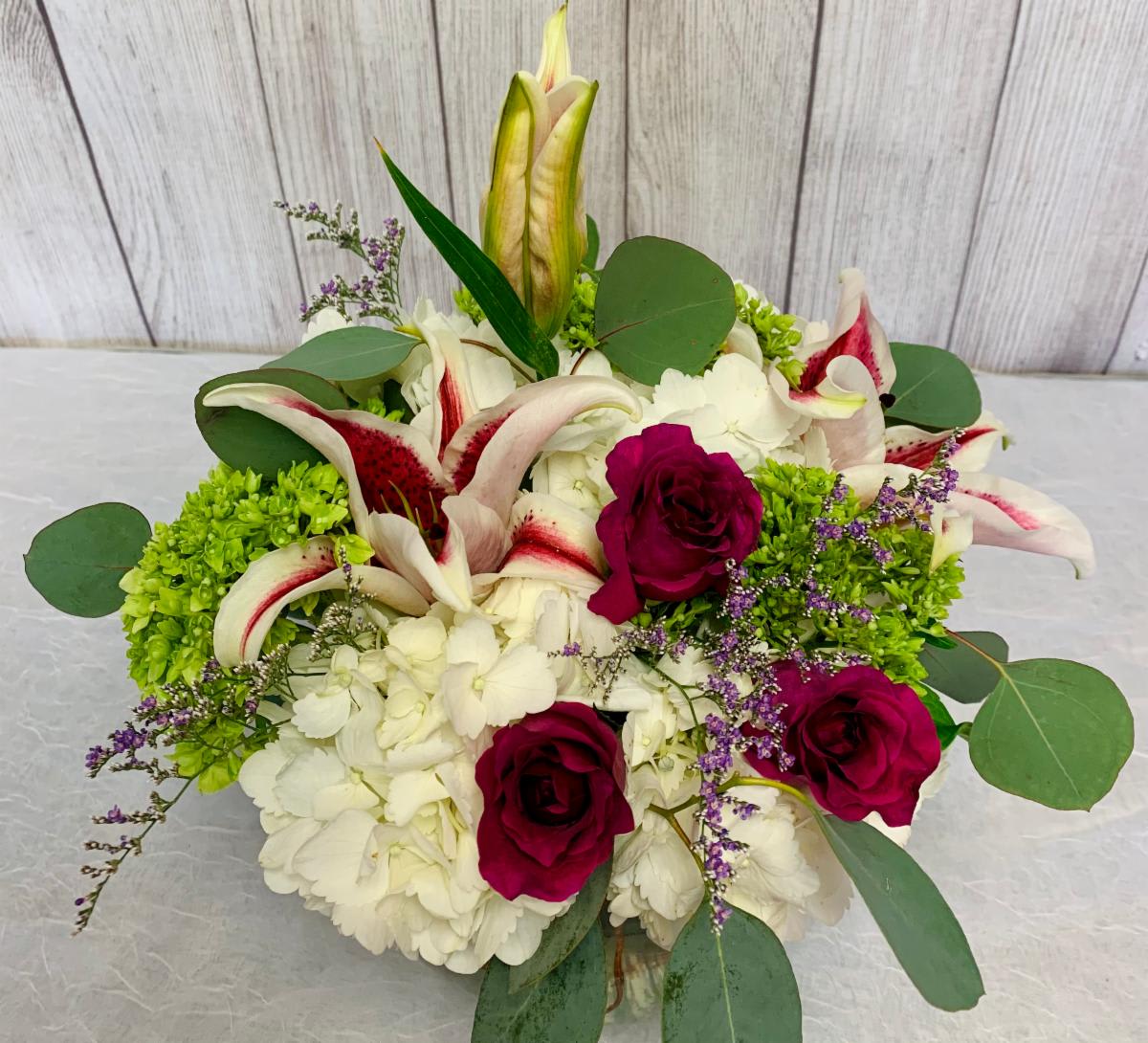 V123 - A compact arrangement with hydrangeas and roses. 
