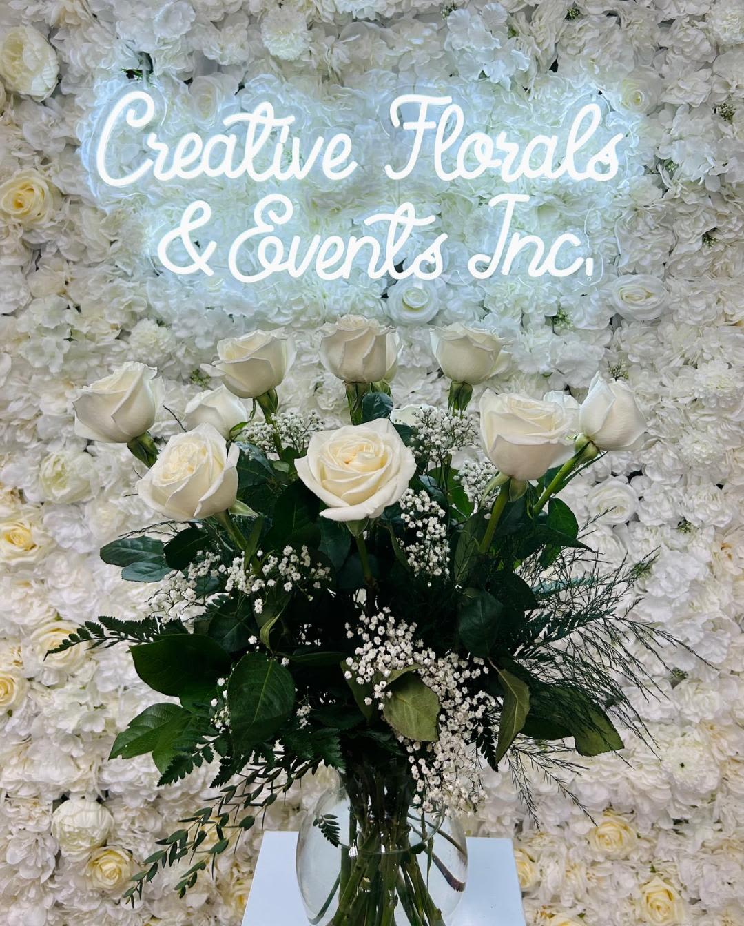 V135 - A dozen white garden roses arranged in tall clear glass vase with mixed greenery and filler. 
