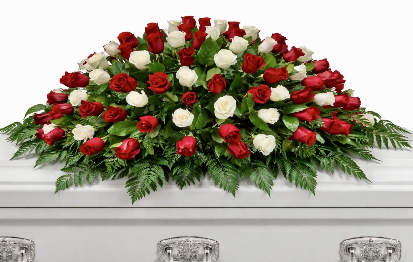 Puré Remembrance - A classic and elegant casket spray designed with a lush bed of fresh greenery and a timeless mix of red and white roses. Full, balanced, and graceful, this piece is a beautiful expression of love, honor, and remembrance, perfect for a final tribute. Oversized Casket Spray