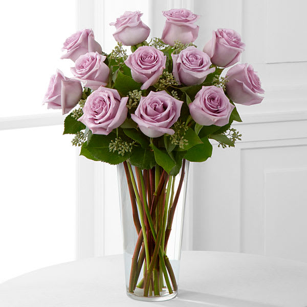 Lavender Rose Bouquet - An enchanting bouquet of lavender roses sweetly touches her heart. Paired with delicate greens in a stylish glass vase these lovely roses are a perfect gift. Please note that lavender roses can vary in color depth. Vase style may vary