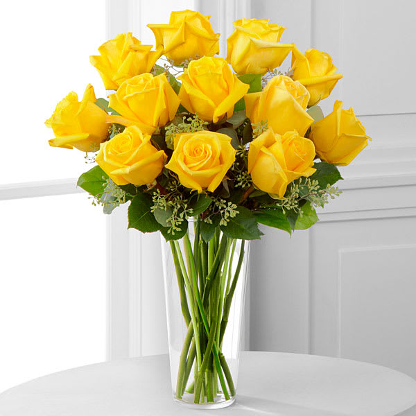 Yellow Rose Bouquet - Sunny yellow roses are a cheery and wonderful gift. Celebrate a birthday anniversary graduation or any occasion with this lively bouquet arranged with delicate greens in a clear glass vase. Vase style may vary