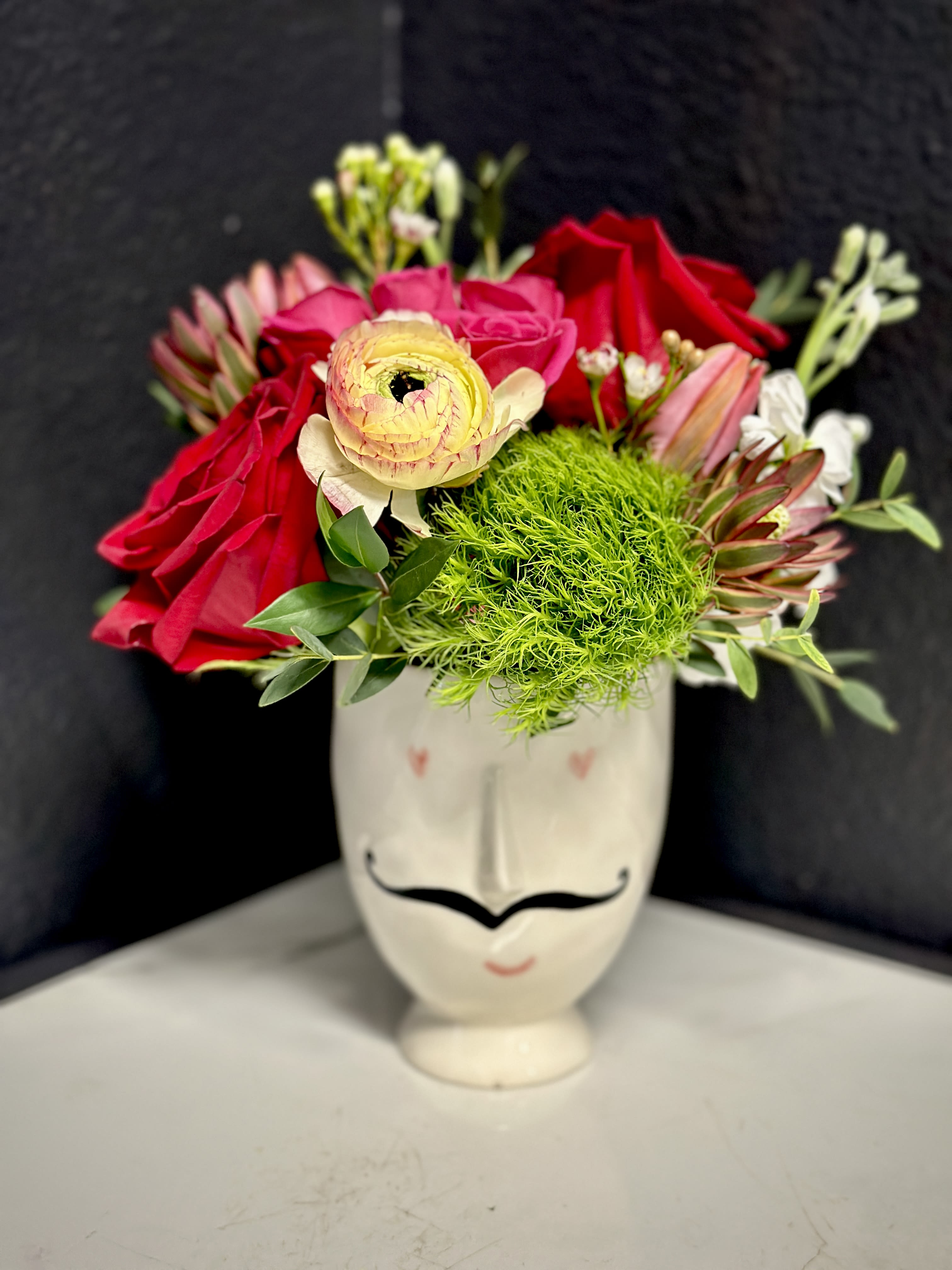 Marcel  - Monsieur Marcel is here to spread some love. This adorable ceramic vase is filled with a designer's choice mix of blooms.  Overall design is approximately 8" tall. Vase/pot Size:3.5"x 4" Floral varieties/vase may vary but will be of similar quality and style.  