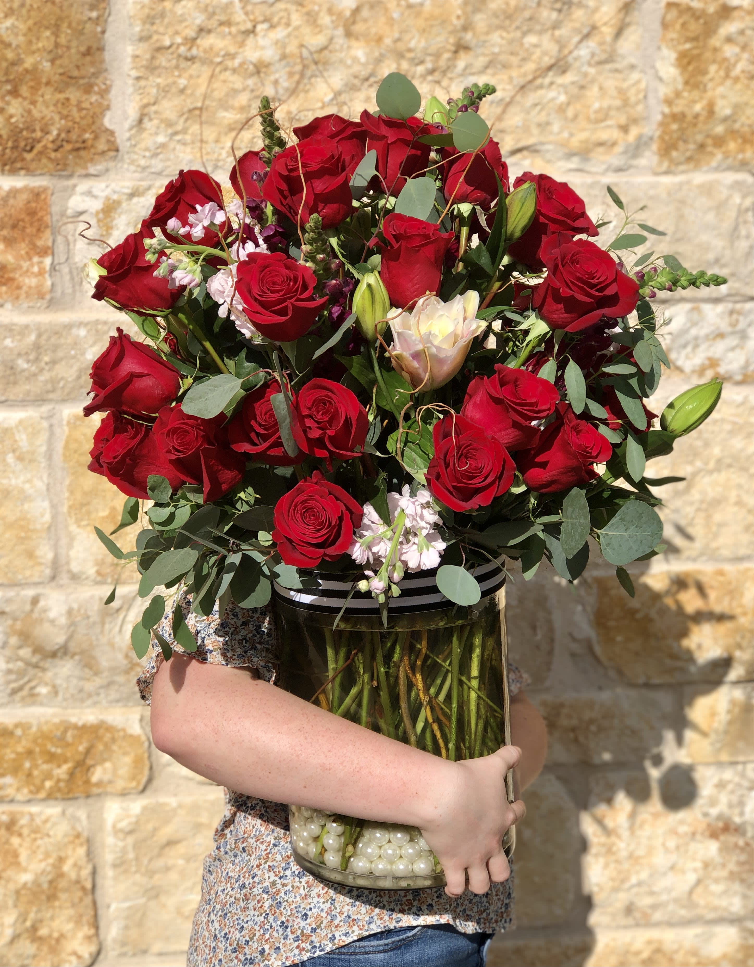 Lavish Red Roses &amp; Lilies - An elegant design that's sure to WOW. A tall arrangement of 40 or upgrade for 50 premium roses, accented with seasonal blossoms and greenery for a lush display. A perfect way to celebrate a milestone birthday or anniversary or celebrate an extra special Valentine. Arranged in a clear glass vase with pearls or river stones.   Overall design is approximately 28" tall. 