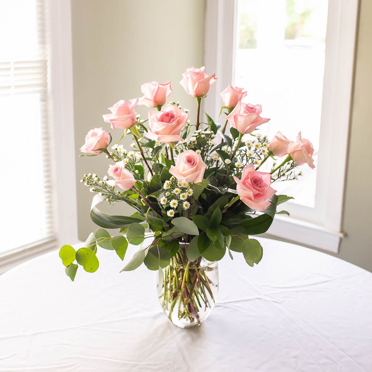 Pretty in Pink - "Pretty in Pink" is a classic dozen pink roses with accent flower and premium greenery, designed in a clear glass vase and sure to impress.  Pink Roses symbolize Gratitude and Grace.  Color may vary to Light Pink or Hot Pink. 