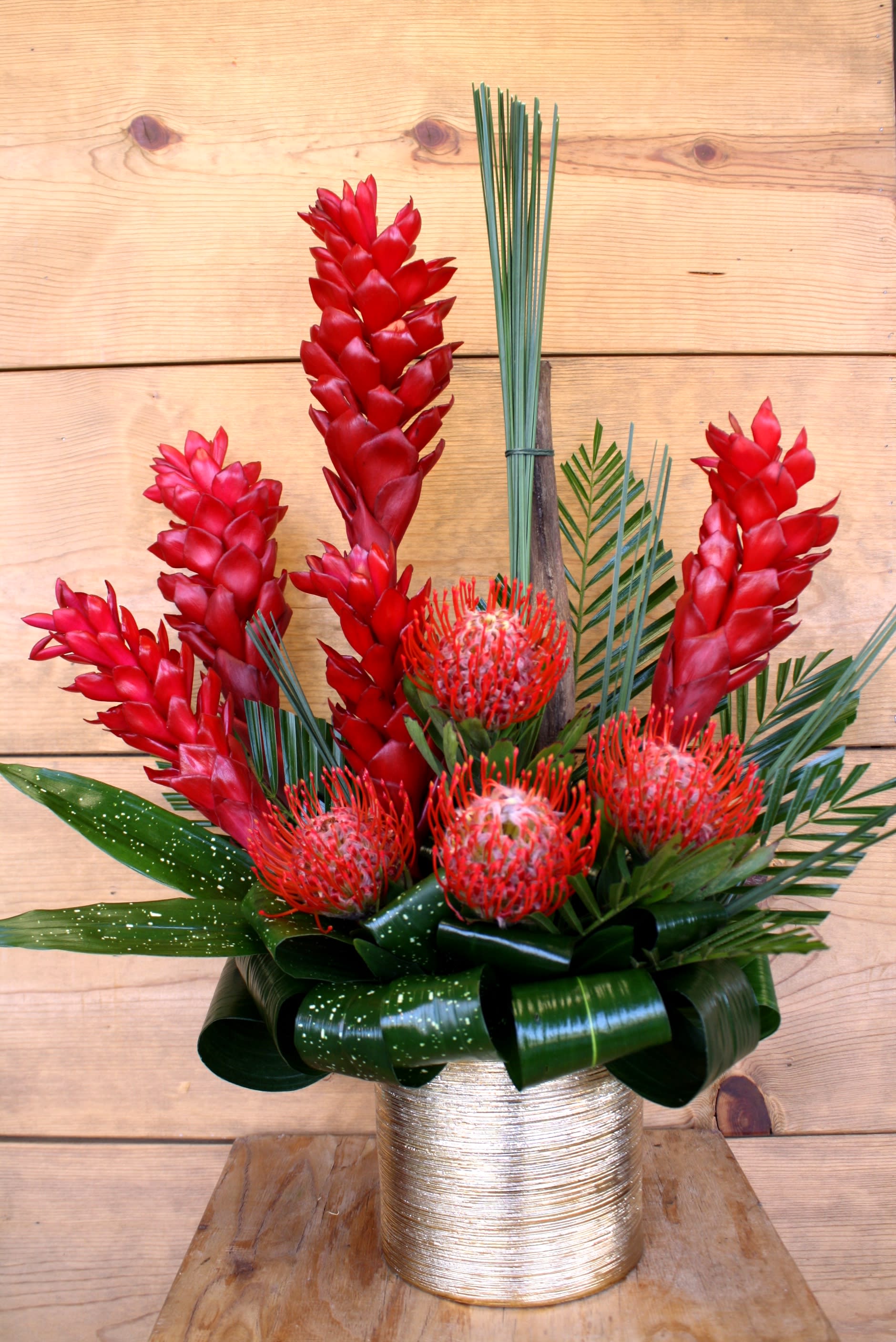 Fiji - Valentine's Day 2019 Collection, a stunning gold vase filled with red lush tropicals and greens. 