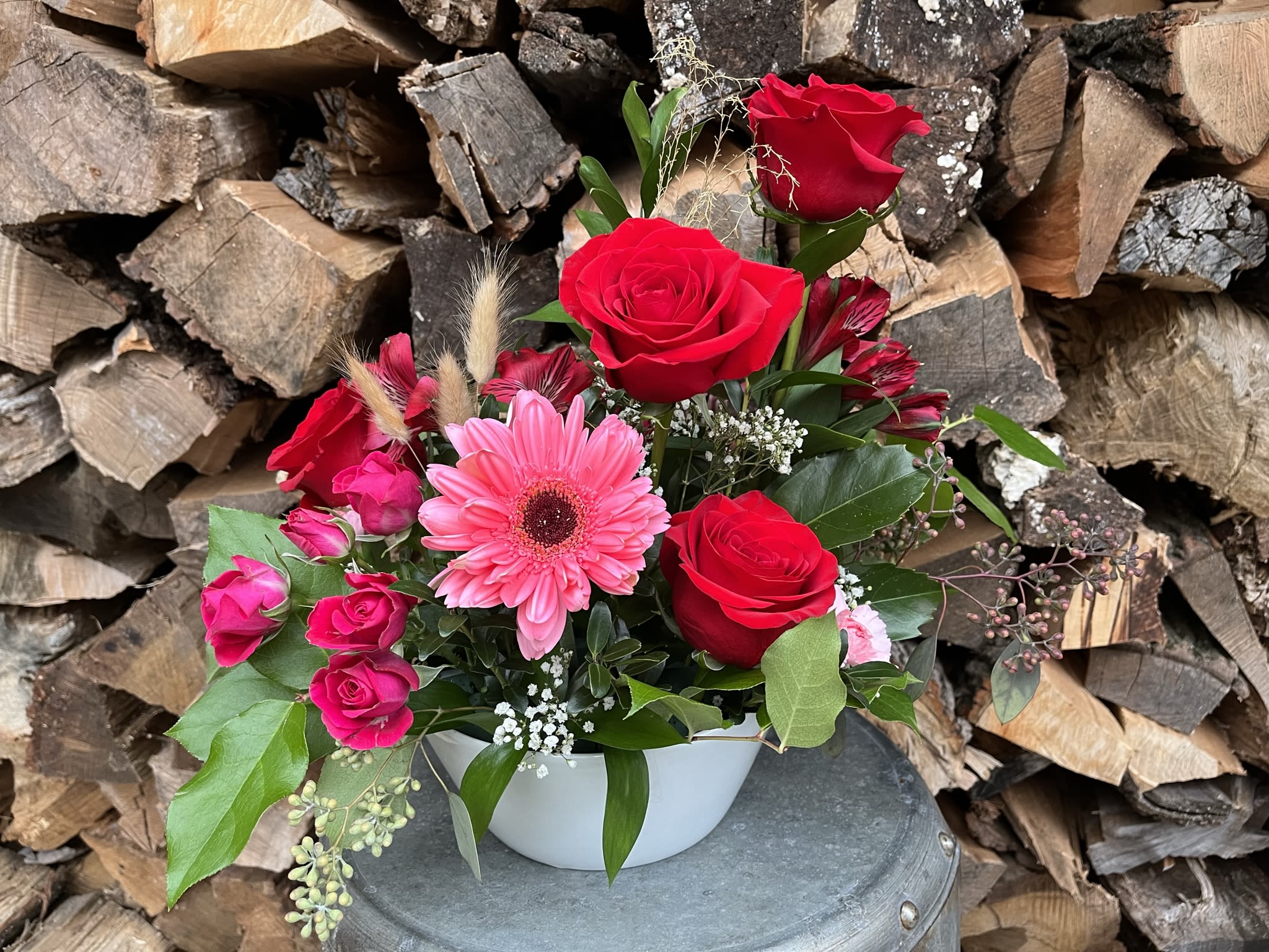 Rose in Bloom - Classic red roses designed in a white bowl accented with Gerber daisies, alstroemeria and local eucalyptus and pines.  