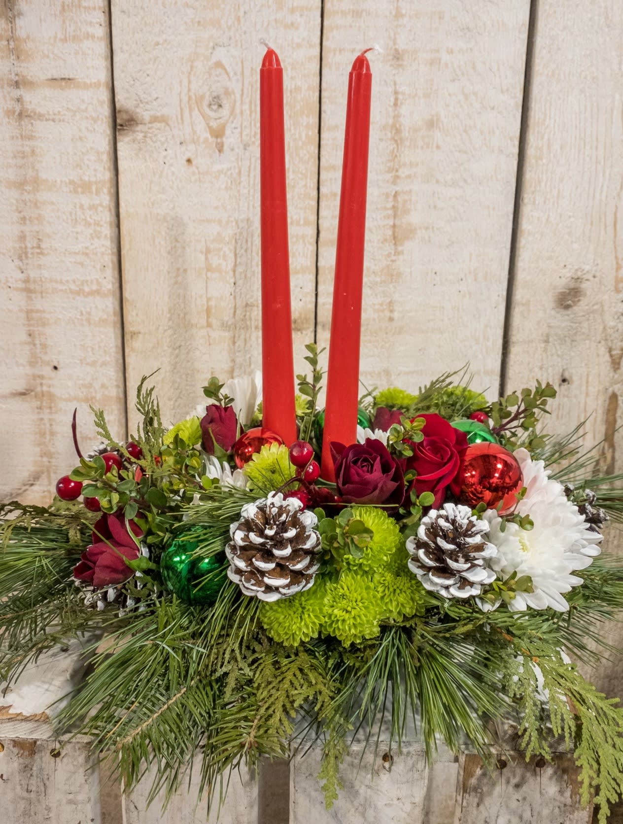 Classic Centerpiece - This timeless centerpiece makes a wonderful gift.  Green mums, pinecones, red taper candles, roses, berries and ornaments complete this elegant arrangement.