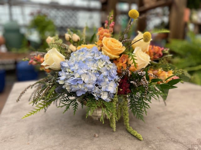 Blue Skies &amp; Sunshine - A cheerful arrangement with blue hydrangea, yellow and peach roses, bright billy balls, and mixed greenery, accented with soft seasonal flowers for a fresh, garden look.