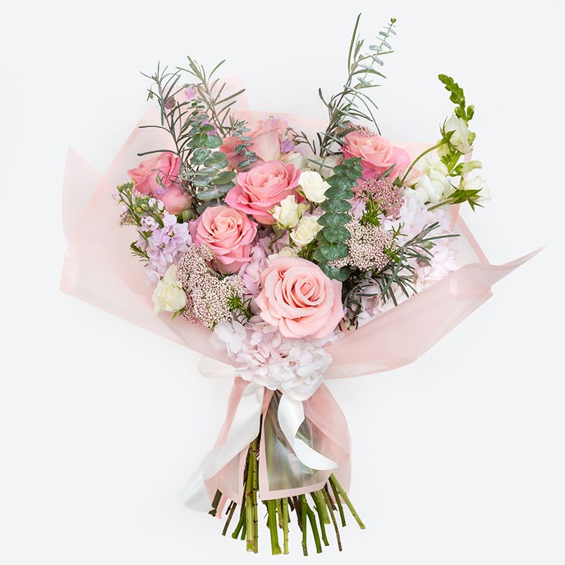 Blush Crush Bouquet - Fall in love at first sight with our Blush Crush Bouquet. This Valentine’s Day arrangement features lush blush and pink roses paired with delicate white blooms, soft pastel accents, and fresh seasonal greenery. Hand-tied and wrapped in airy blush paper, this romantic bouquet is perfect for Valentine’s Day, anniversaries, or simply sending a little love. Sweet, elegant, and timeless—Blush Crush is made to make hearts flutter. 