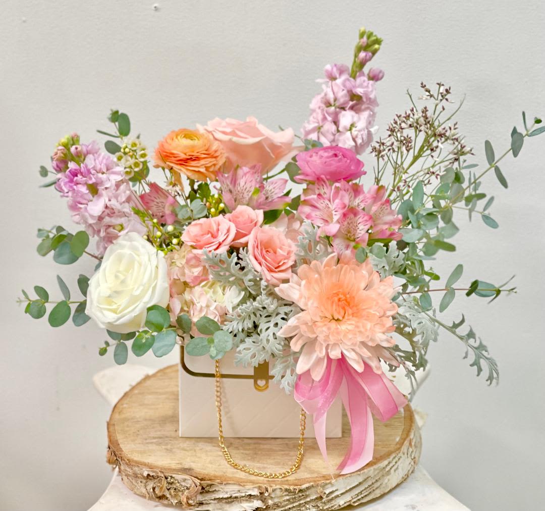 Blush Purse -   Product Information Theme Colors: Shades of white, peachy, pink  Featured Blooms: Roses, spay roses, Stock, Chrysanthemums, Hydrangeas, Alstroemeria, Ranunculus, and greeneries in blush bag.  HK Flowers have a uniqueness of florals and seasonal blooms, certain flowers or colors may not be available as each season affects the availability, color, size, and shape of each floral bloom. Some flowers may be substituted accordingly.  Photos are used as a reference for the color palette and is NOT indicated of the final product. We ask for your trust in us that we will pick out the best seasonal available blooms, while still capturing the arrangements' theme and colors mentioned above