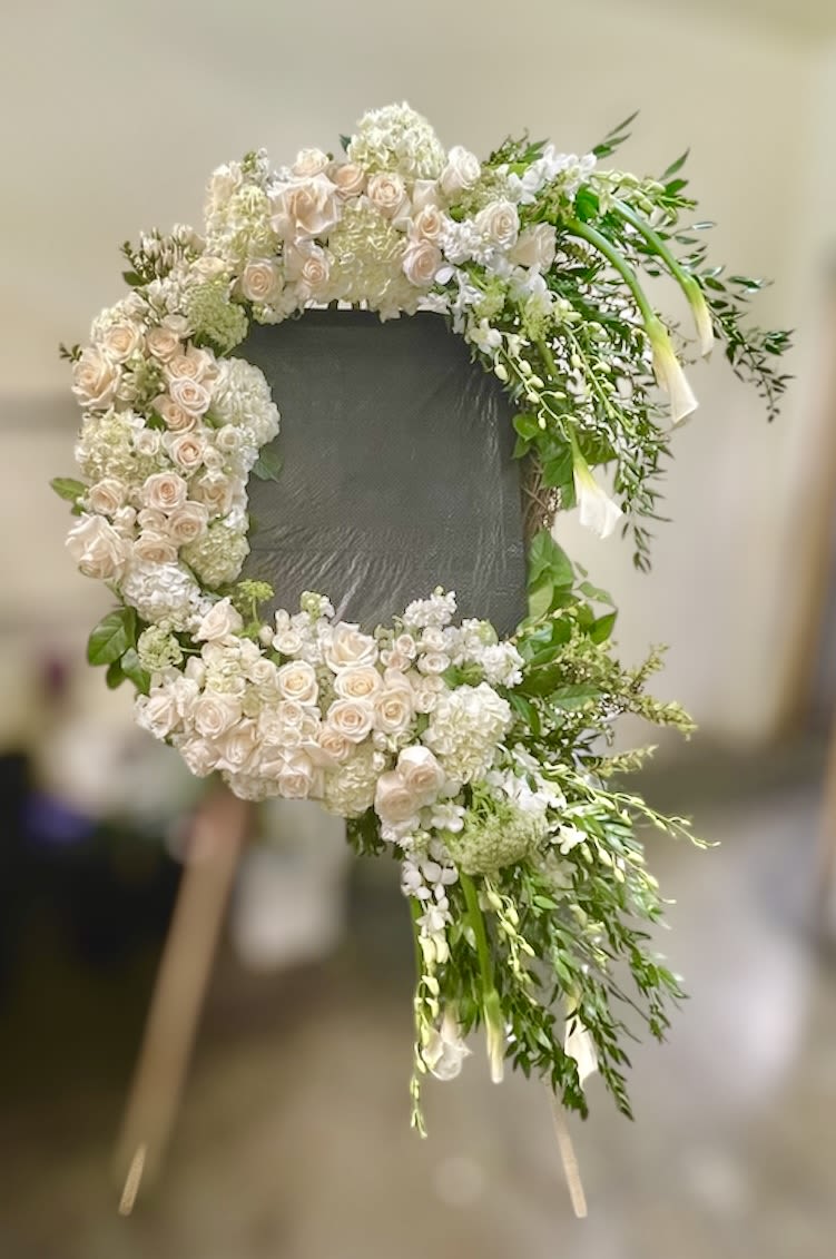 Funeral arrangement for picture -  Theme Colors: Shades of white and green  Featured Blooms: Roses, Hydrangeas, Tulips and  you also can contact us to give the size of your photo frame so we can place it in the middle of your funeral arrangement.   HK Flowers have a uniqueness of florals and seasonal blooms, certain flowers or colors may not be available as each season affects the availability, color, size, and shape of each floral bloom. Some flowers may be substituted accordingly.  Photos are used as a reference for the color palette and is NOT indicated of the final product. We ask for your trust in us that we will pick out the best seasonal available blooms, while still capturing the arrangements theme and colors mentioned above.