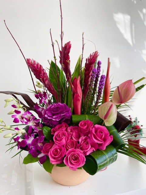 Honoulu - Theme Colors: Shades of pink, red and green  Featured Blooms: Roses, Orchids, Cabbage, Anthuriums, Ginger, Dense Blazing Star and greens  HK Flowers have a uniqueness of florals and seasonal blooms, certain flowers or colors may not be available as each season affects the availability, color, size, and shape of each floral bloom. Some flowers may be substituted accordingly.  Photos are used as a reference for the color palette and is NOT indicated of the final product. We ask for your trust in us that we will pick out the best seasonal available blooms, while still capturing the arrangements theme and colors mentioned above.