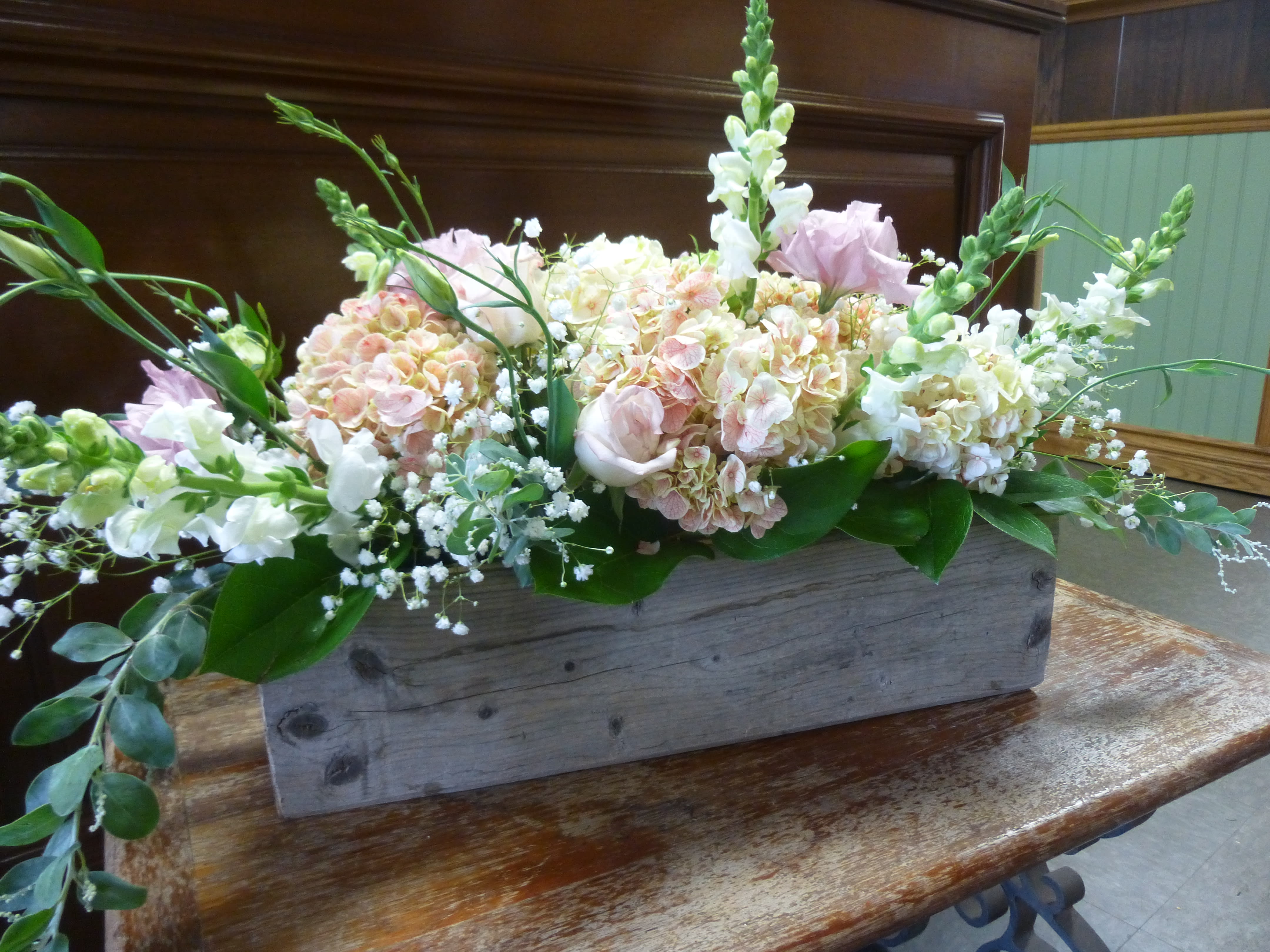 Celebrating Engagement - Recipe: Hydragaes, Snapdragon, Lisianthus, Roses, Baby Breath, Greens in a local hand-made wooden box. Availability: All year round Dimensions: Center piece in wooden box. 11" long regular 14" long premium 