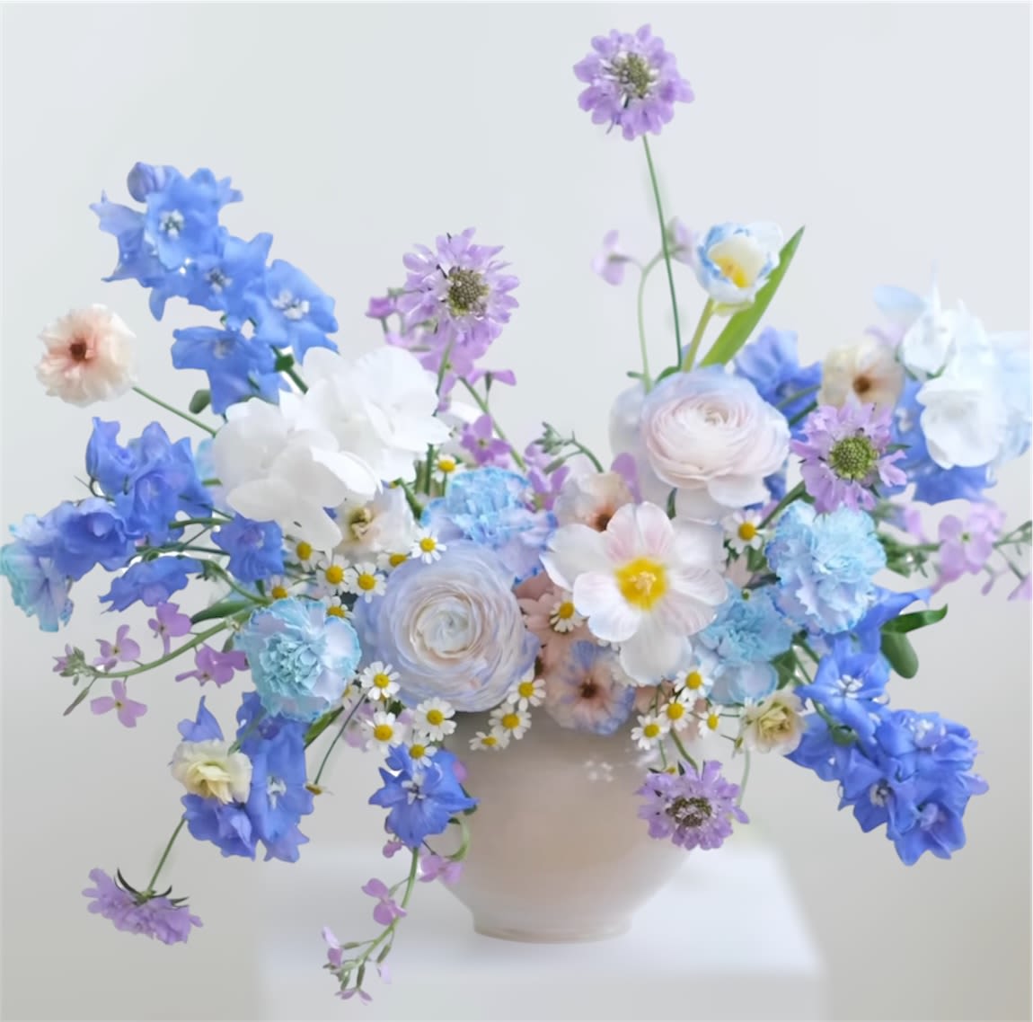 Skylar - Theme Colors: Shades of light blue.  Featured Blooms: Tulips, Scabiosa,Ranunculus, Delphinium, Daisy, Carnations, Seasonal Blooms  HK Flowers have a uniqueness of florals and seasonal blooms, certain flowers or colors may not be available as each season affects the availability, color, size, and shape of each floral bloom. Some flowers may be substituted accordingly.  Photos are used as a reference for the color palette and is NOT indicated of the final product. We ask for your trust in us that we will pick out the best seasonal available blooms, while still capturing the arrangements theme and colors mentioned above.