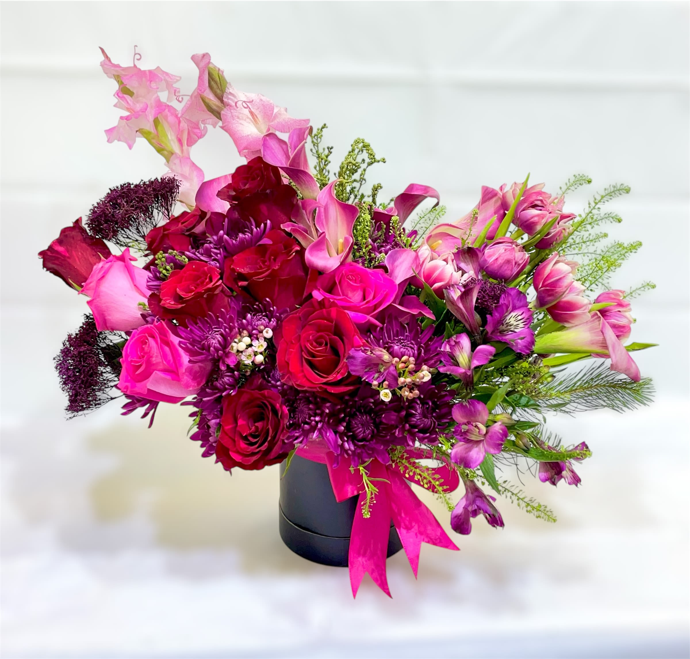 Red kiss - Theme Colors: Shades of Red &amp; pink  Featured Blooms: Roses, alstroemeria, tulips, calla lily, gladiolus  HK Flowers have a uniqueness of florals and seasonal blooms, certain flowers or colors may not be available as each season affects the availability, color, size, and shape of each floral bloom. Some flowers may be substituted accordingly. arrangement design in Round black box . Photos are used as a reference for the color palette and is NOT indicated of the final product. We ask for your trust in us that we will pick out the best seasonal available blooms, while still capturing the arrangements theme and colors mentioned above.