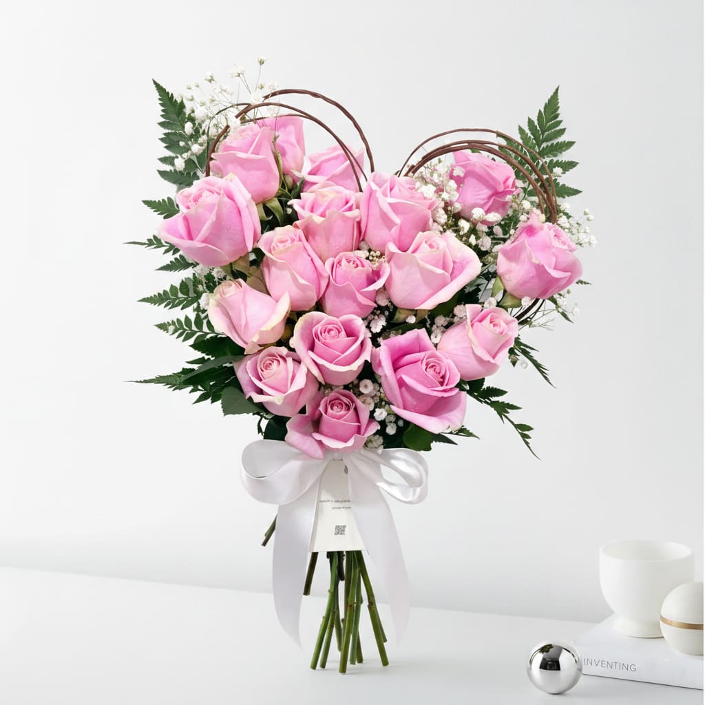 Given with Care™  - Given with Care is a soft, heart-shaped bouquet of blush pink roses, gently hand-tied with delicate greenery and finished with a flowing white ribbon. Thoughtful and warm in tone, this Valentine’s bouquet expresses affection through tenderness, sincerity, and quiet intention. 