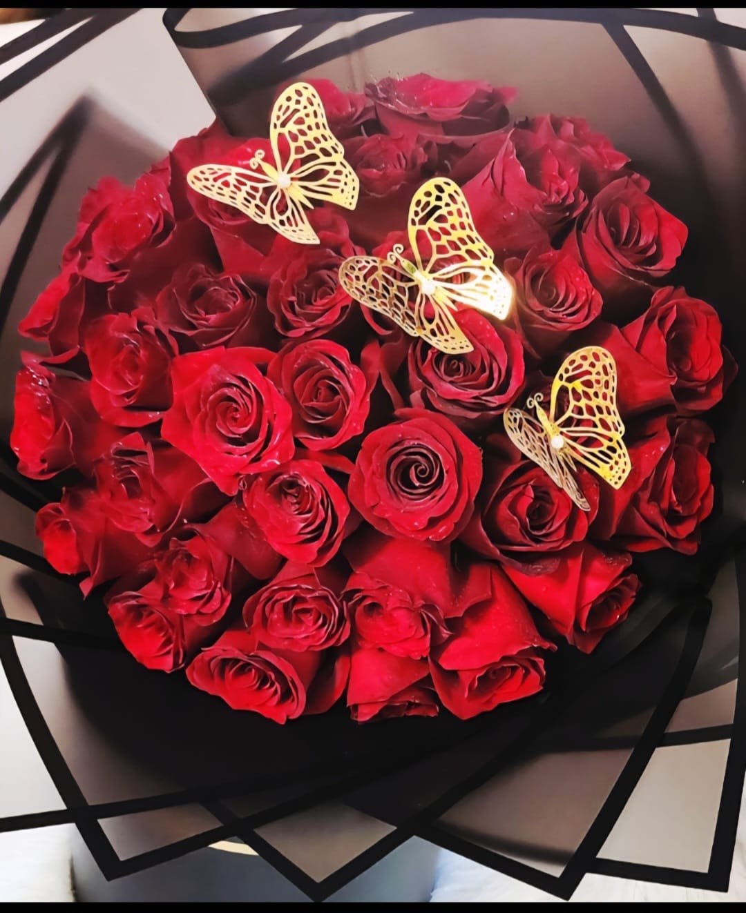 Khloe - Charming arrangement of red roses with butterfly picks.