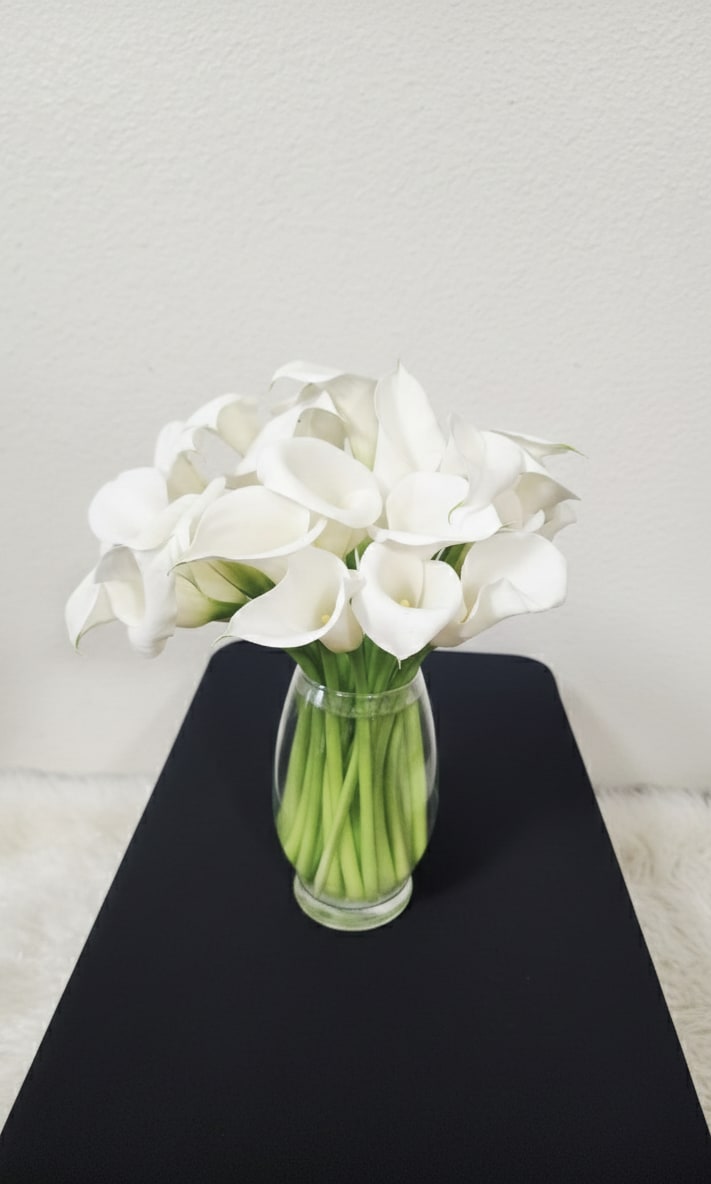 Lily - An elegant bouquet of 24 white calla lilies, perfectly composed in a clear glass vase.
