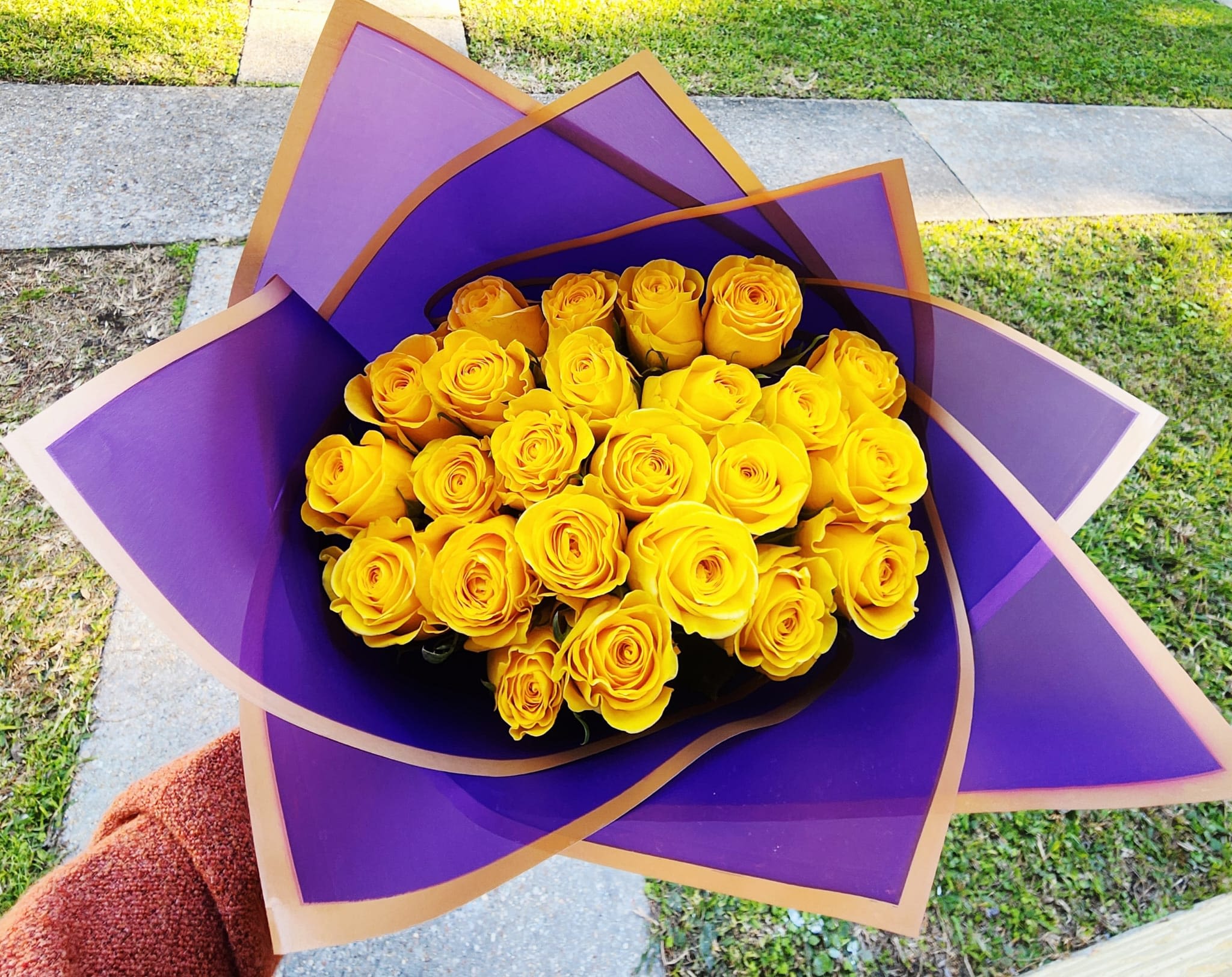 Royal Bloom - A striking cluster of 24 yellow roses radiates warmth, perfectly framed by rich royal purple wrapping that adds depth and drama. Like sunshine crowned in royalty; designed to make a statement.
