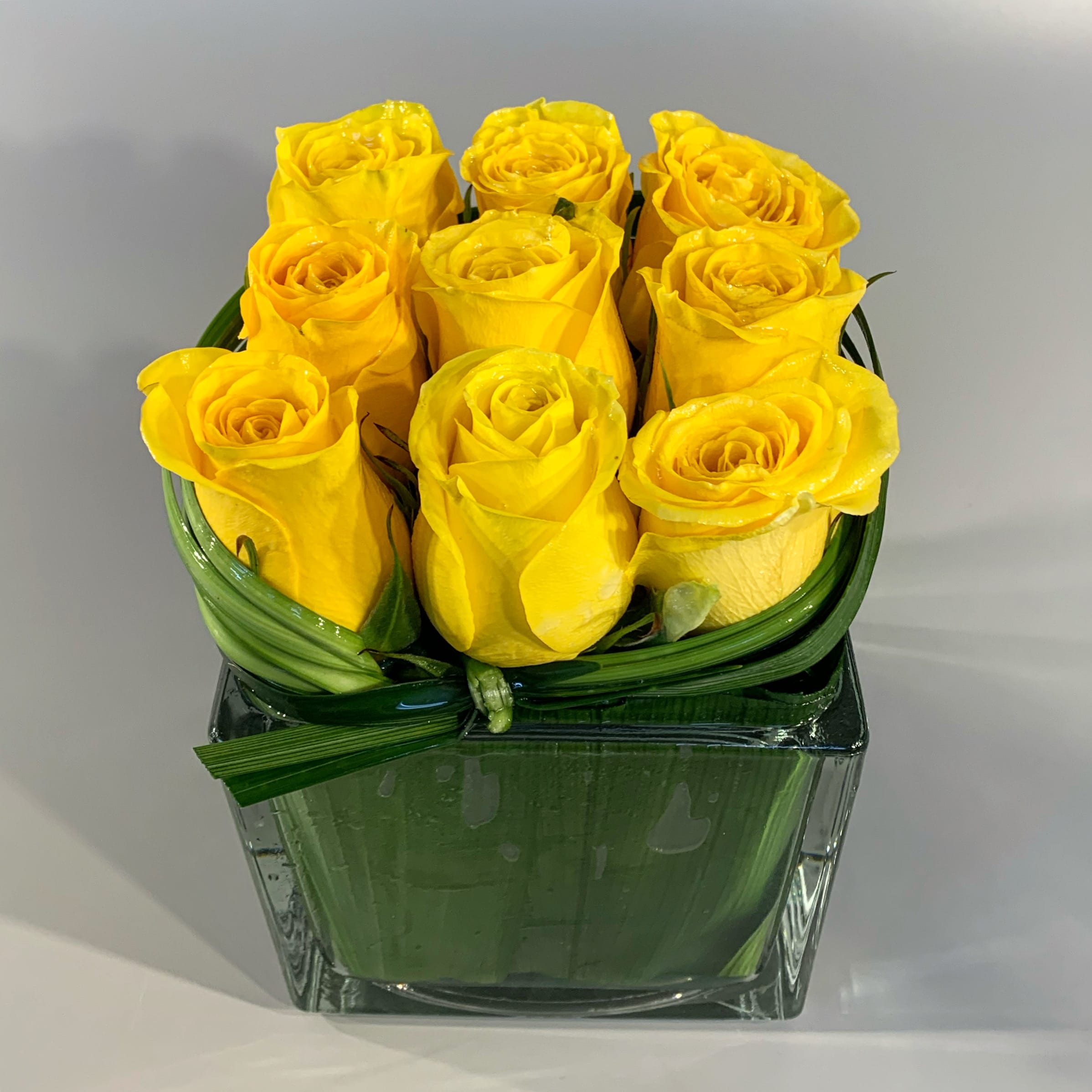 CHIC - A modern design using a simple pave' of roses designed in a leaf-lined glass vessel. Also available with red, white or hot-pink roses. Please note any color changes in the special instructions. 