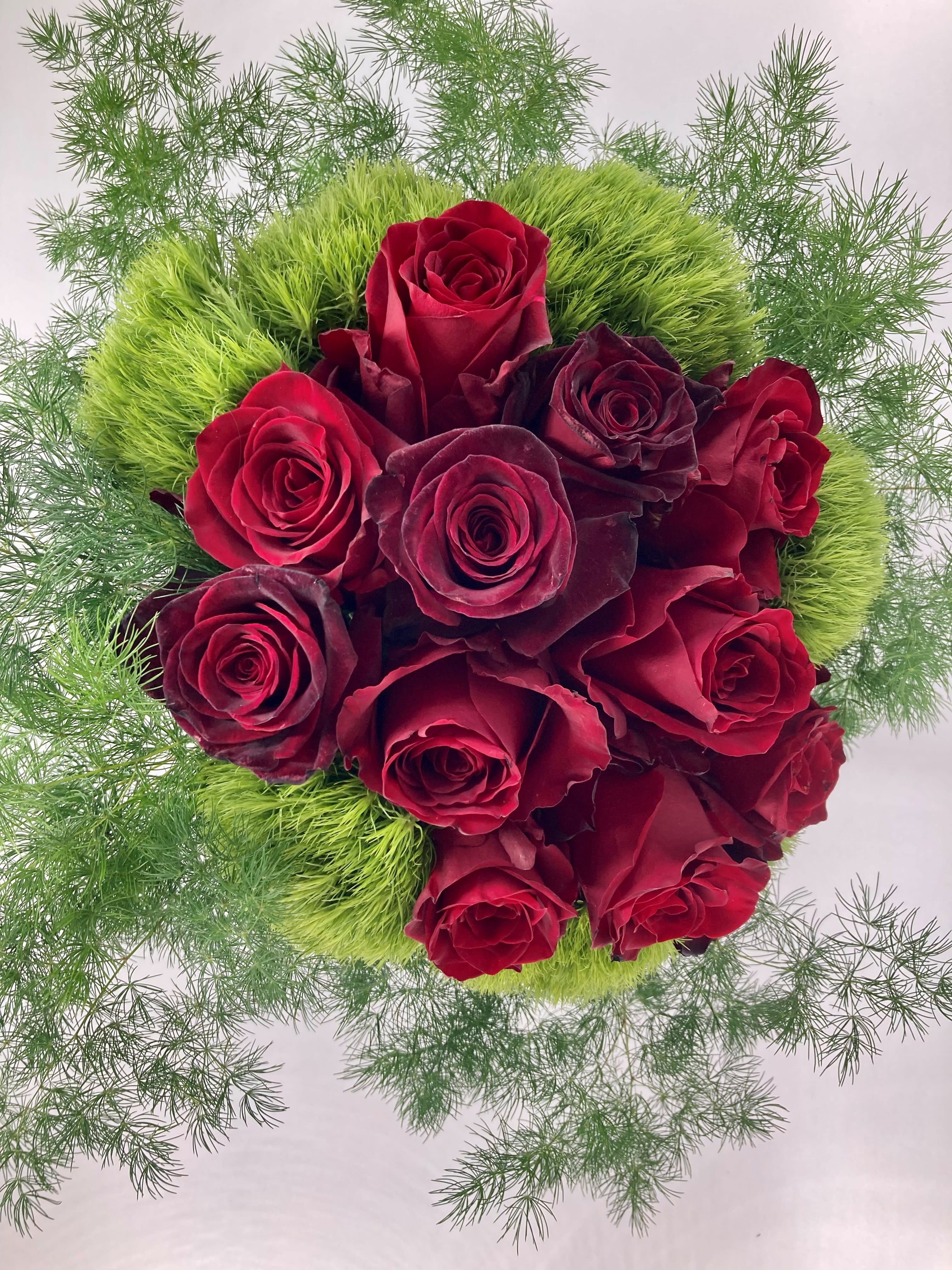 Low and Lush Red and Dark Roses - A beautifully designed white cut glass vase filled with a mixture of lush deep dark red roses nestled in an expanse of salal and green trix - this one will pull at anyone's heartstrings.