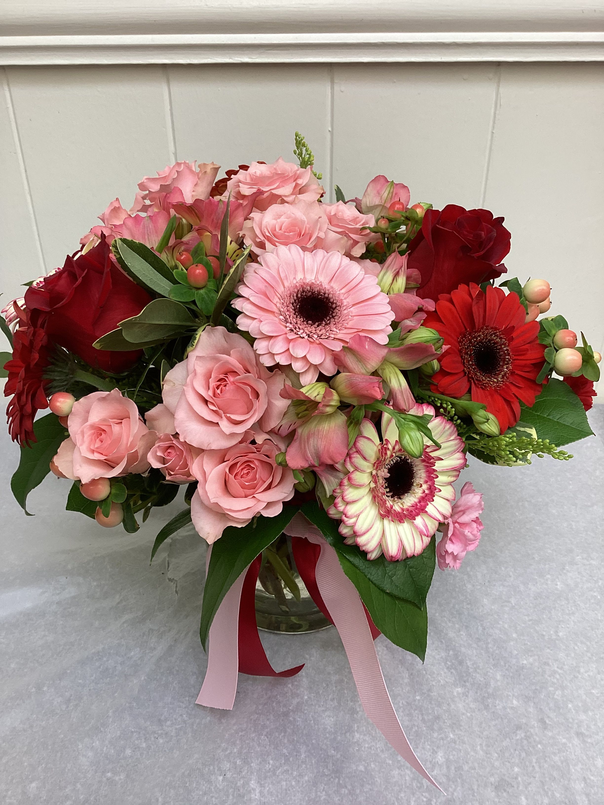 Rose et Rouge  - This beautiful arrangement features a variety of reds and pinks. Using red roses pink and red gerb daises, pink alstroemeria, hypericum berries, and pink spray roses. With a touch of pink and red mini carnations. 