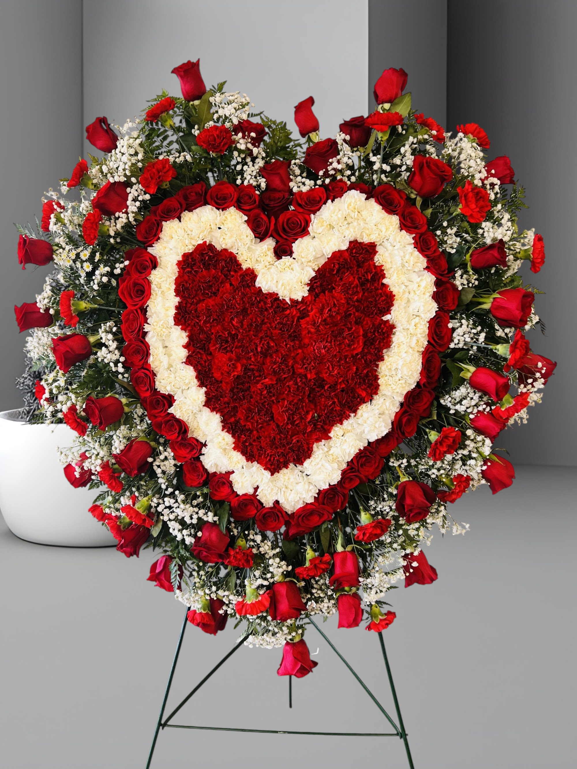 Eternal Love - The passing of someone we love deeply requires a special tribute. Our full heart standing arrangement of fresh white blooms, accented by red roses, red &amp; white carnations cascading down adorned with a red satin ribbon, will help you express the devotion and sympathy in your heart