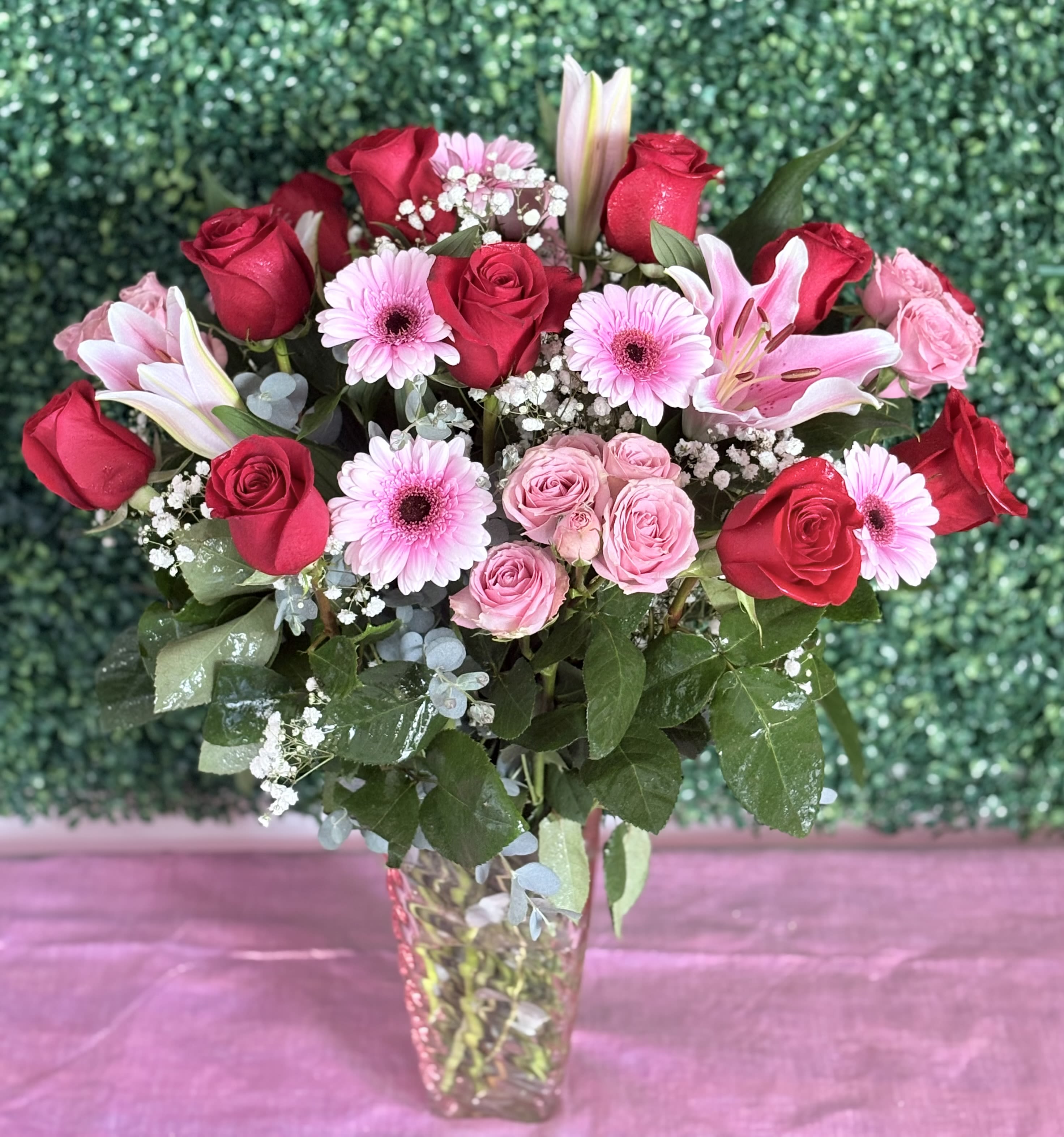 Sweetheart vase arrangement - Red roses, lilies, baby’s breath, spray roses, gerbera daisies, and eucalyptus arranged in a vase, perfect for your sweetheart. 
