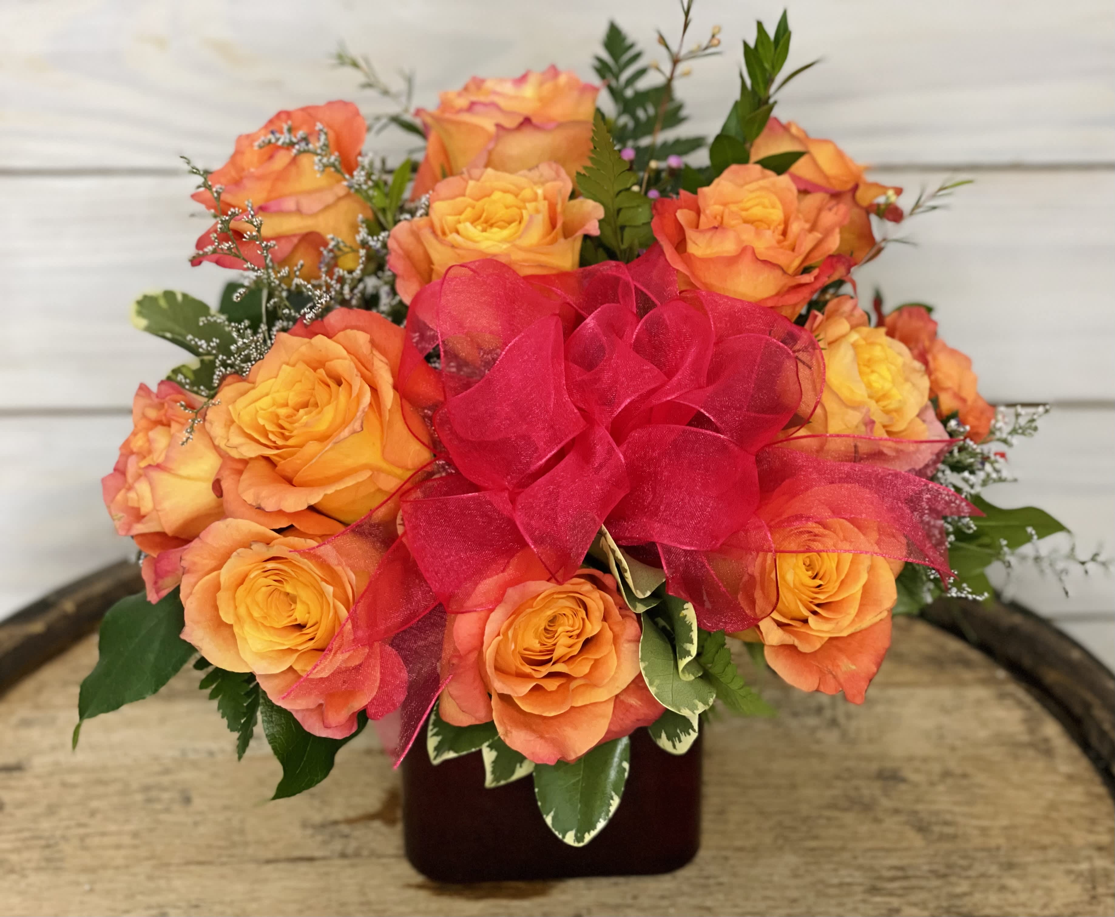 Dozen Free Spirit Roses - 12 gorgeous Free Spirit roses in a deep red square vase with filler flower. This rose is a favorite of Brandi's(owner). It's also known as the sherbet rose in Butterfields as it reminds us of sherbet ice cream. 
