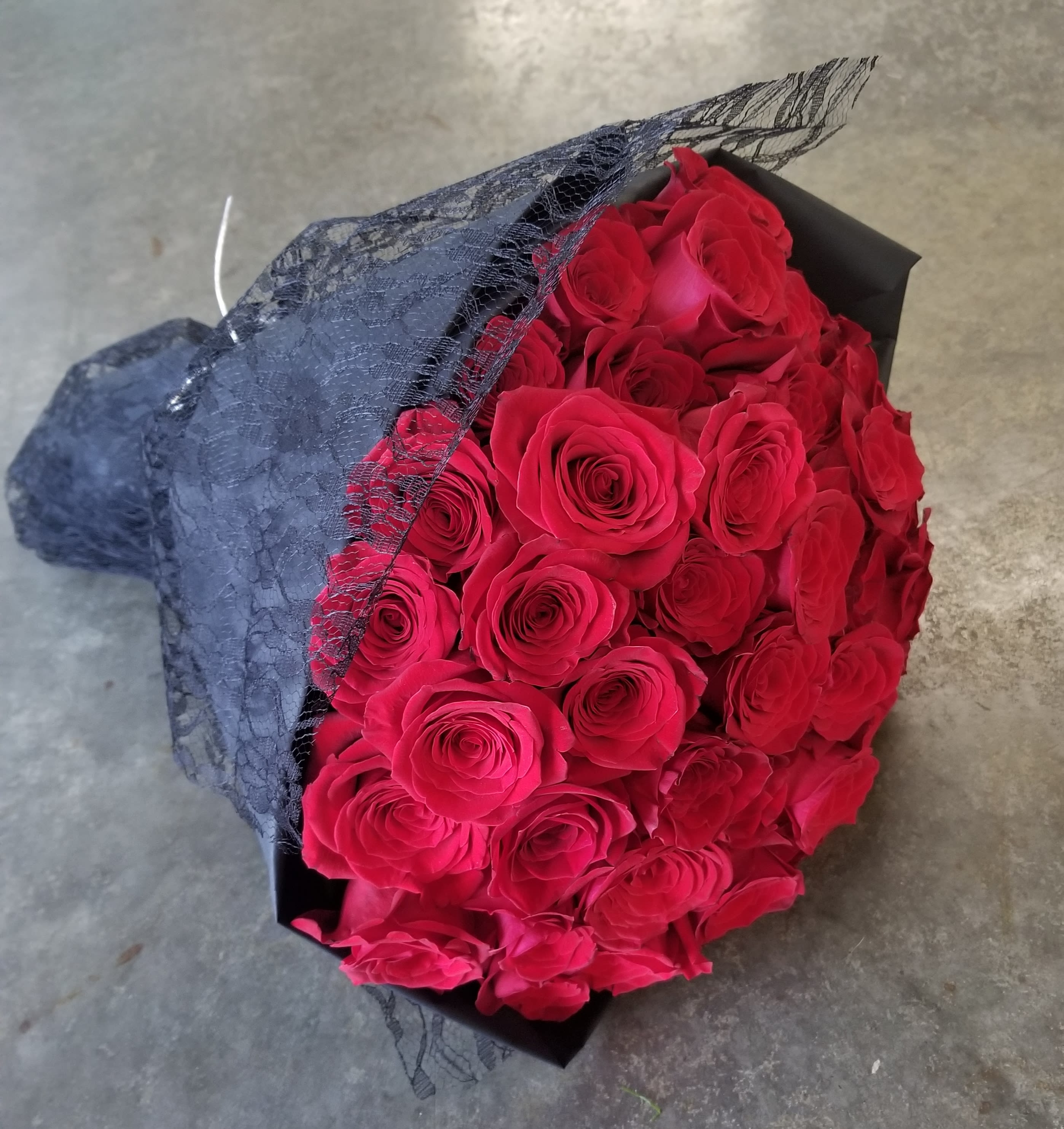 Hand Tied Red Roses - Select this stunning hand tied bouquet of 50 medium stem red roses in a rounded style wrapped in black paper.  Premium version has 99 medium stem red roses wrapped in the same style. 