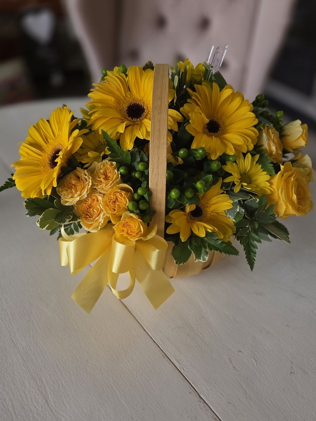Sunshine Therapy Basket - Brighten anyone's day with our Sunshine Therapy Basket! This charming arrangement features vibrant yellow gerbera daisies, mini spray roses, and golden chrysanthemums, accented with fresh greenery and green hypericum berries. Presented in a natural wooden basket and tied with a cheerful yellow satin bow, it’s a beautiful way to share warmth, happiness, and positive energy.