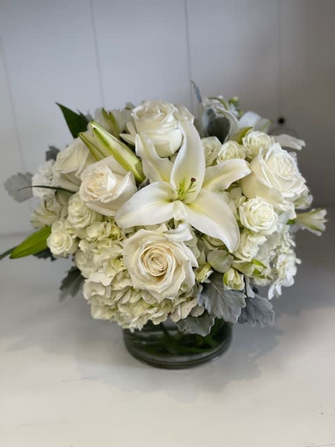 Moon Light - "Moon Light" is the epitome of simple elegance, featuring an all-around arrangement of pure white blooms with varying textures. This fragrant design includes fragrant white lilies, delicate white stock, and soft white roses, creating a clean and timeless look that brings peace and sophistication to any setting.
