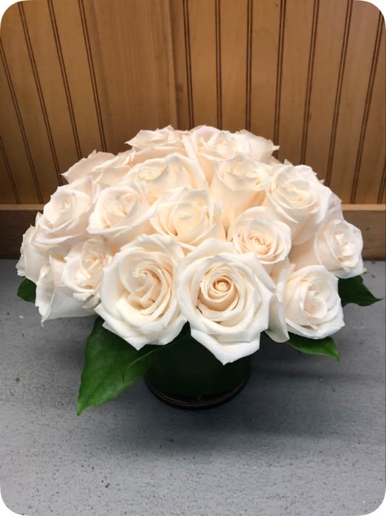 The Lovely  -  Gorgeous pure white roses. Arranged perfectly, tight and tailored in a clear glass vase with an aspidistra leaf. So classy. Version shown is the deluxe.