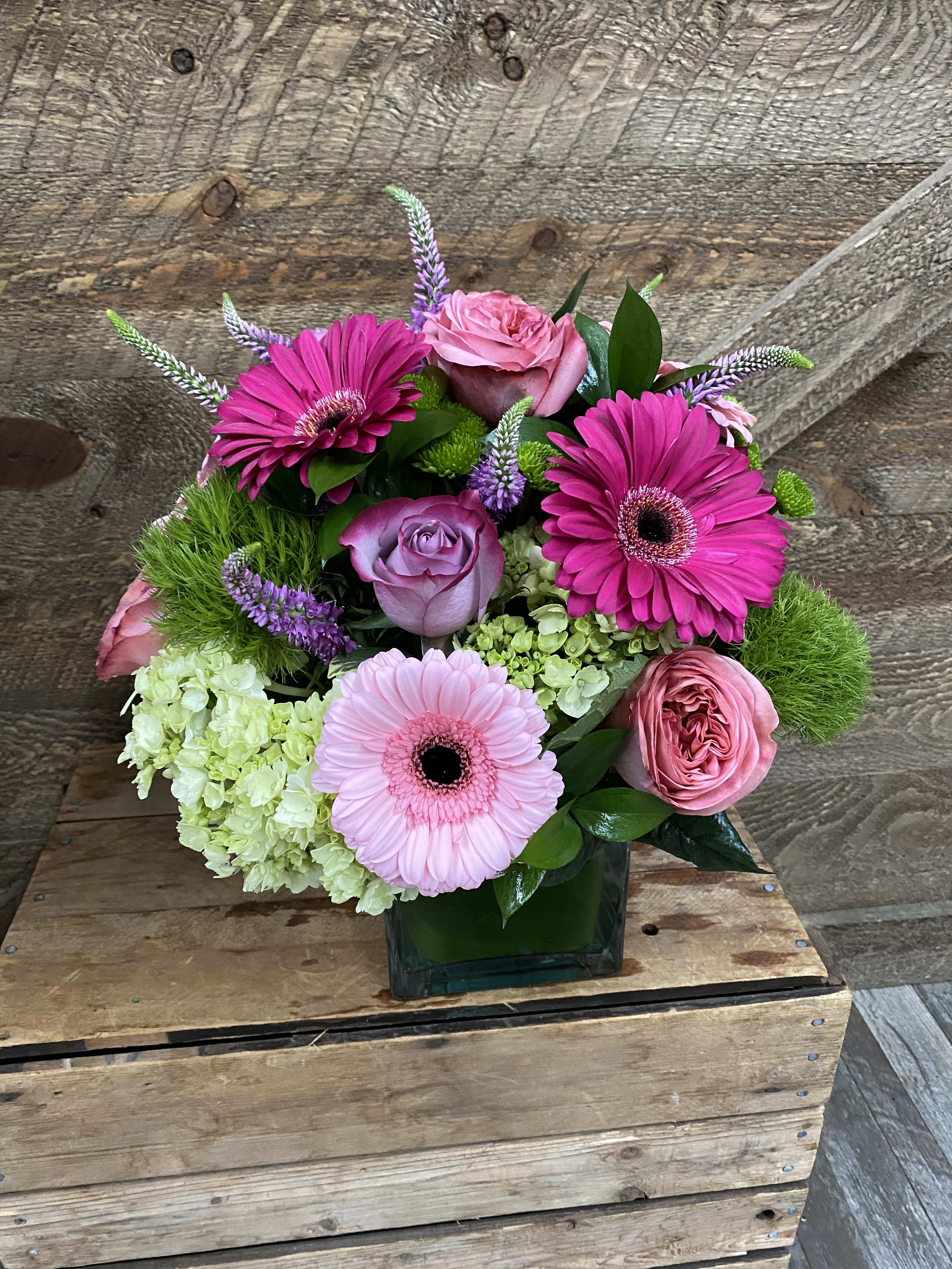 The Melrose  - LOVE THIS ONE! Gerbera daisies, hydrangea, veronica and roses. Designed compact in a clear glass leaf wrapped vase. Version shown is the deluxe.