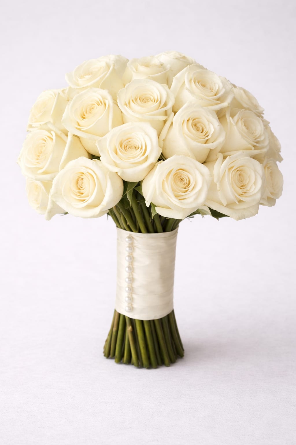 Elegant Bridal Bouquet - This traditional white bridal bouquet is a lavish celebration of fine large-headed roses. The subtle shades of white give a sense of timeless elegance. And the soft fragrance of this bouquet will be a lovely accompaniment as she walks up the aisle.  Featuring 24 white roses, white ribbon and pins on one side.