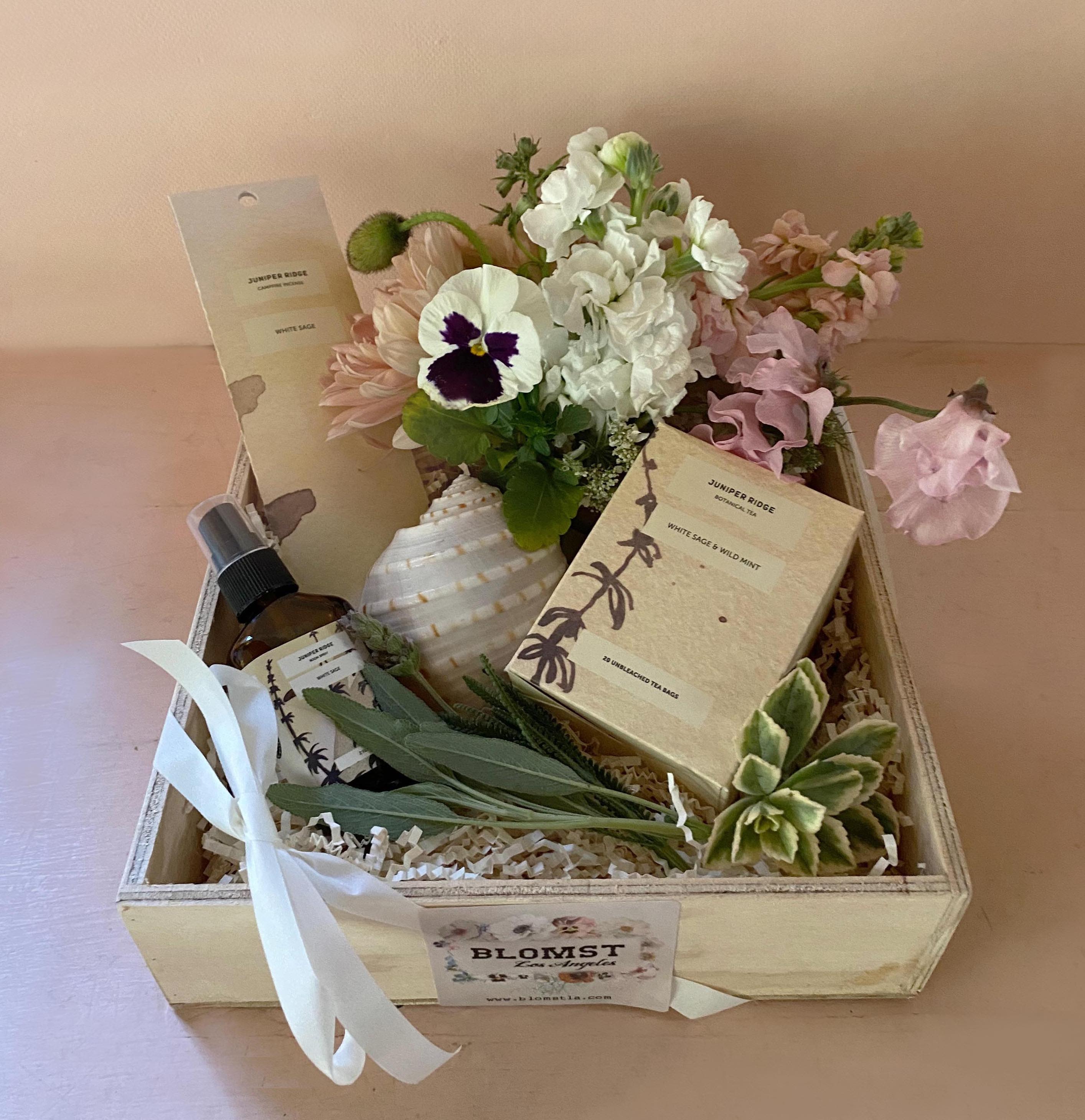 Healing Gift box - This wellness Blomst LA qift box is a thoughtful gift, a warm greeting. Full of lovely and healing prettiness. A scented white sage room spray, white sage incense sticks &amp; lovely white sage + wild mint tea. All natural ingredients made in California from Juniper Ridge. Adorned with a mini Blomst arrangement of fresh flowers and healing sea shell (Seashells have the natural ability to disperse negative energy due to the ocean’s concentration of sea salt. Shells have a protective base in which negativity finds hard to penetrate). Placed in a wooden box (handmade in LA) measuring 10" by 10". Available for hand delivery in LA. We ship gift boxes nationwide, go to our sister site: www.blomstlosangeles.com 