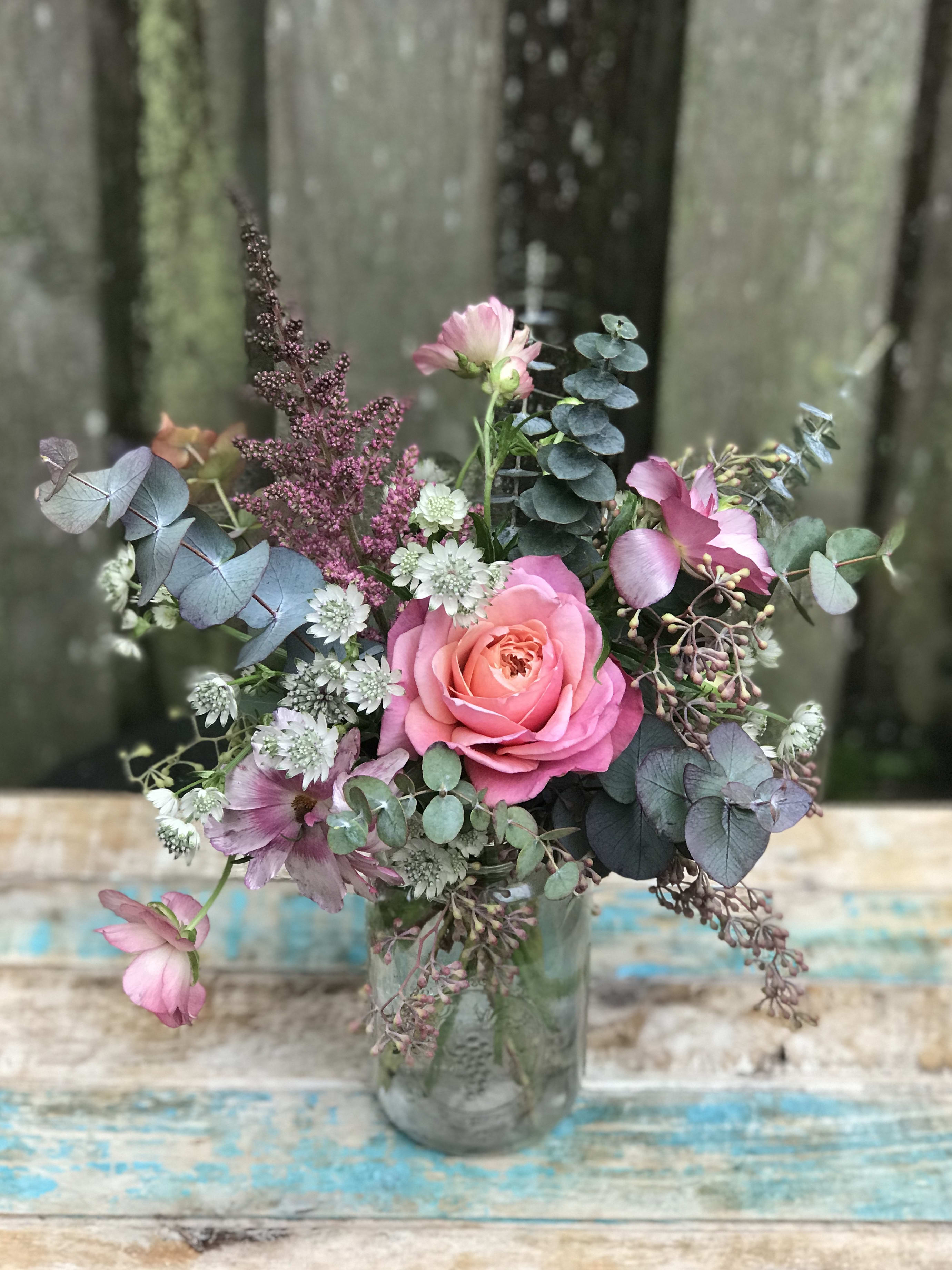 The Sweetest Thing - Spring colors and soft greens in a loose garden style, gathered in a mason jar container are just the sweetest! Colors and blooms vary with the seasonal availability and typically include pinks with pops of white, orange, and yellow with gorgeous greens. 