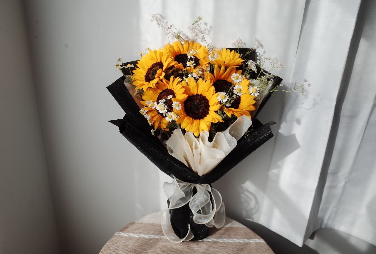 Stage Light - Sunflowers Bouquet for Graduates - Celebrate the climb and the view.   Vibrant sunflowers bloom like medals of honor, accented with white florals and wrapped in classic black and white. This bouquet is a proud, elegant gesture for a graduate who’s reached a milestone and is ready for more.