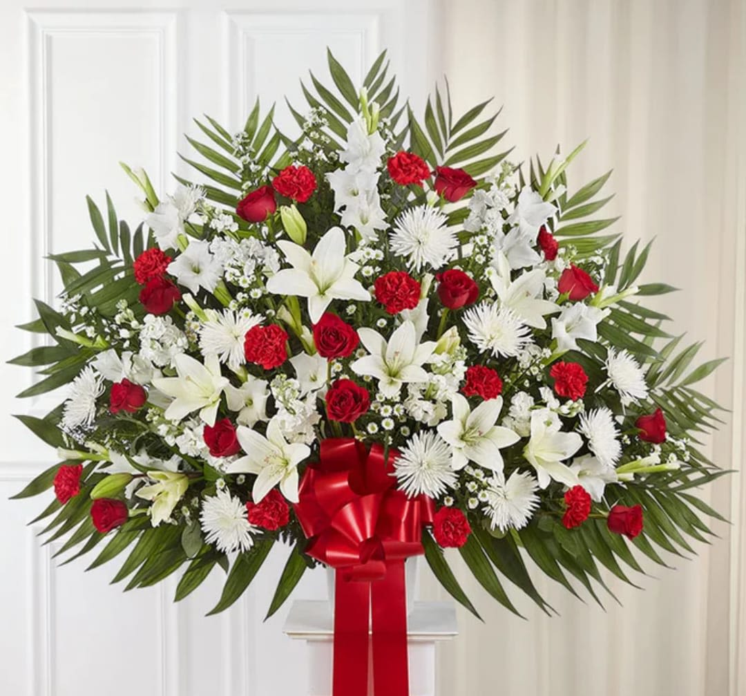Heartfelt Tribute - One-sided floor basket arrangement with red roses and Matsumoto asters, pink Stargazer lilies, white Peruvian lilies (alstroemeria), carnations and football mums; accented with spiral and seeded eucalyptus, baby’s breath, assorted greenery and red bow
