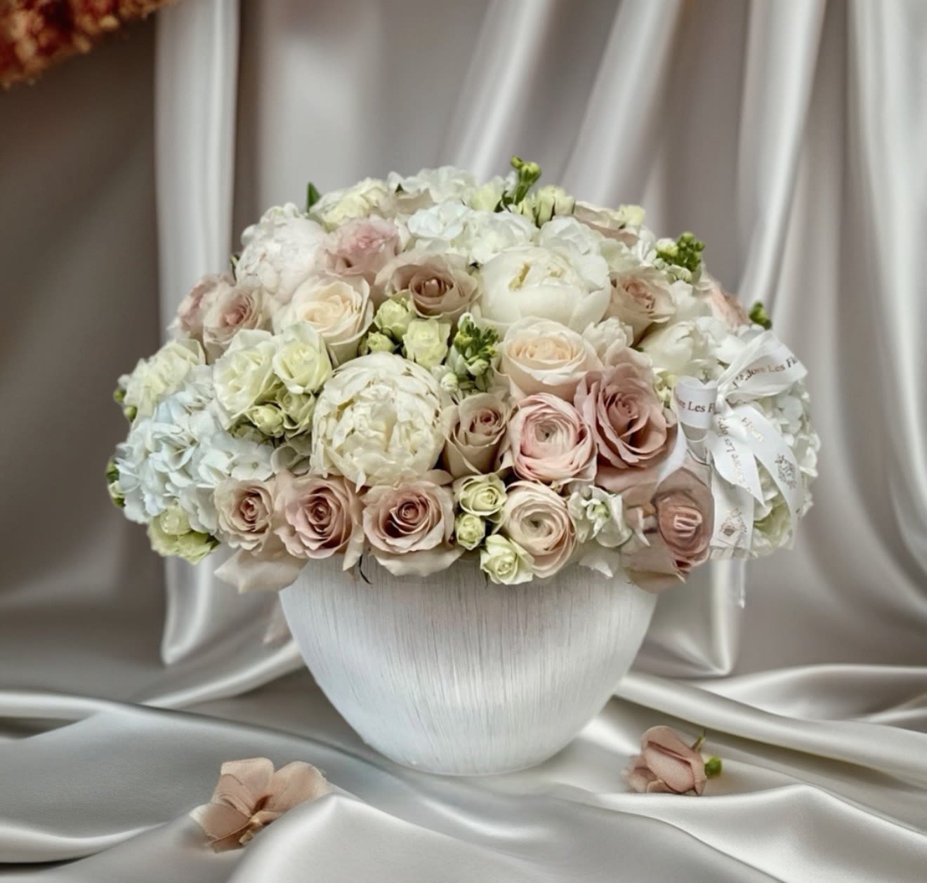 Fifty Shades of love  - The 50 Shadows of Love flower arrangement embraces a soft, romantic aesthetic, featuring a delicate mix of gentle blooms that evoke tenderness and warmth. The arrangement includes velvety roses, airy calla lilies, and fluffy peonies, ranunculus all harmonizing to create a serene atmosphere. Light greenery adds a refreshing touch, while the overall composition is presented in an elegant vase that enhances the softness of the flowers. Delicate ribbons and subtle fairy lights complete the look, making it an enchanting centerpiece for intimate gatherings, weddings, or any celebration of love.