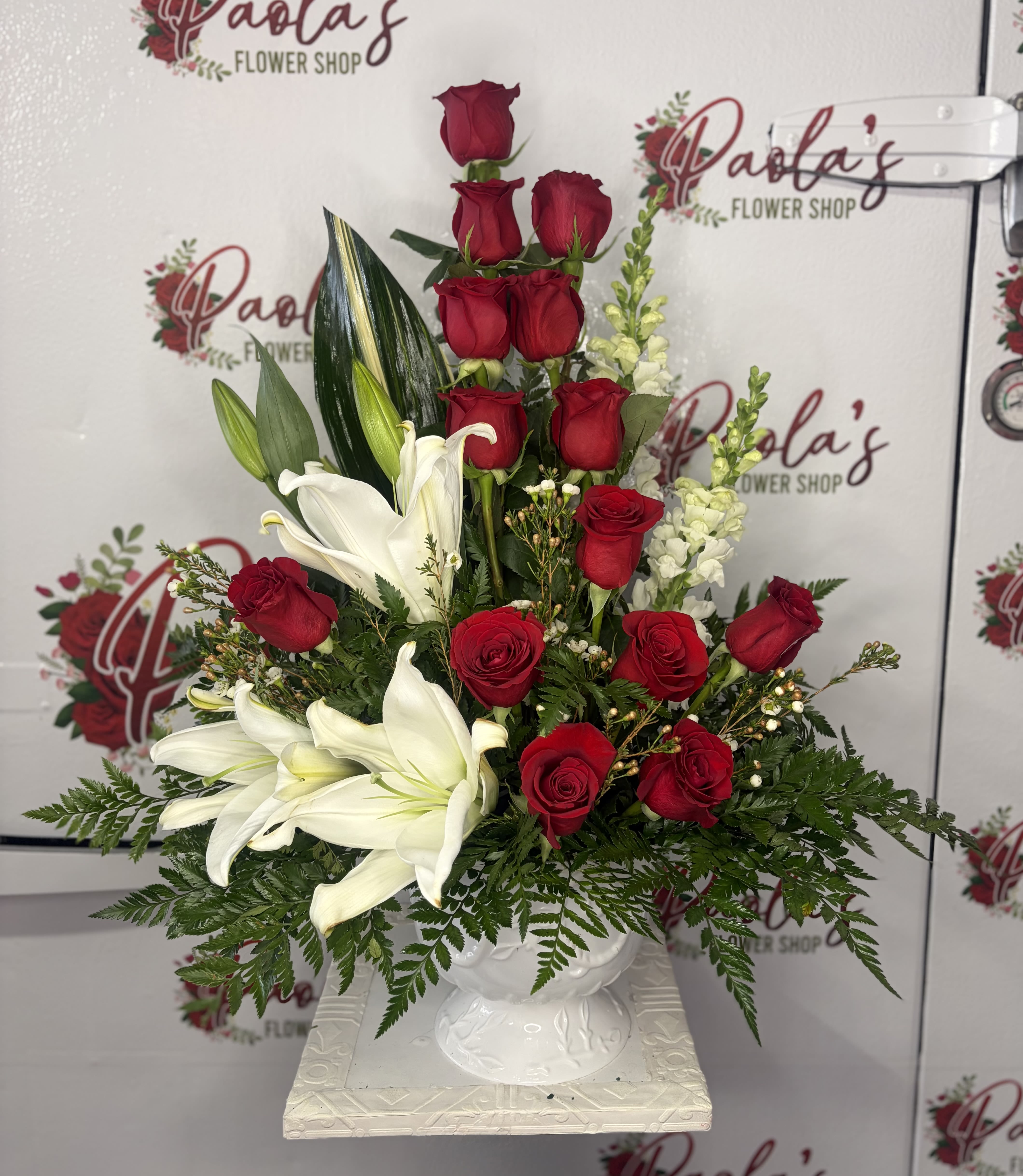 Timeless Love - The Timeless Love Arrangement is a stunning expression of romance and heartfelt emotion. Featuring vibrant red roses paired with elegant white lilies, snapdragons, and lush greenery, this classic floral design symbolizes deep love, devotion, and admiration. Beautifully arranged in a white vase, this arrangement is perfect for Valentine’s Day, anniversaries, or a thoughtful “just because” surprise.