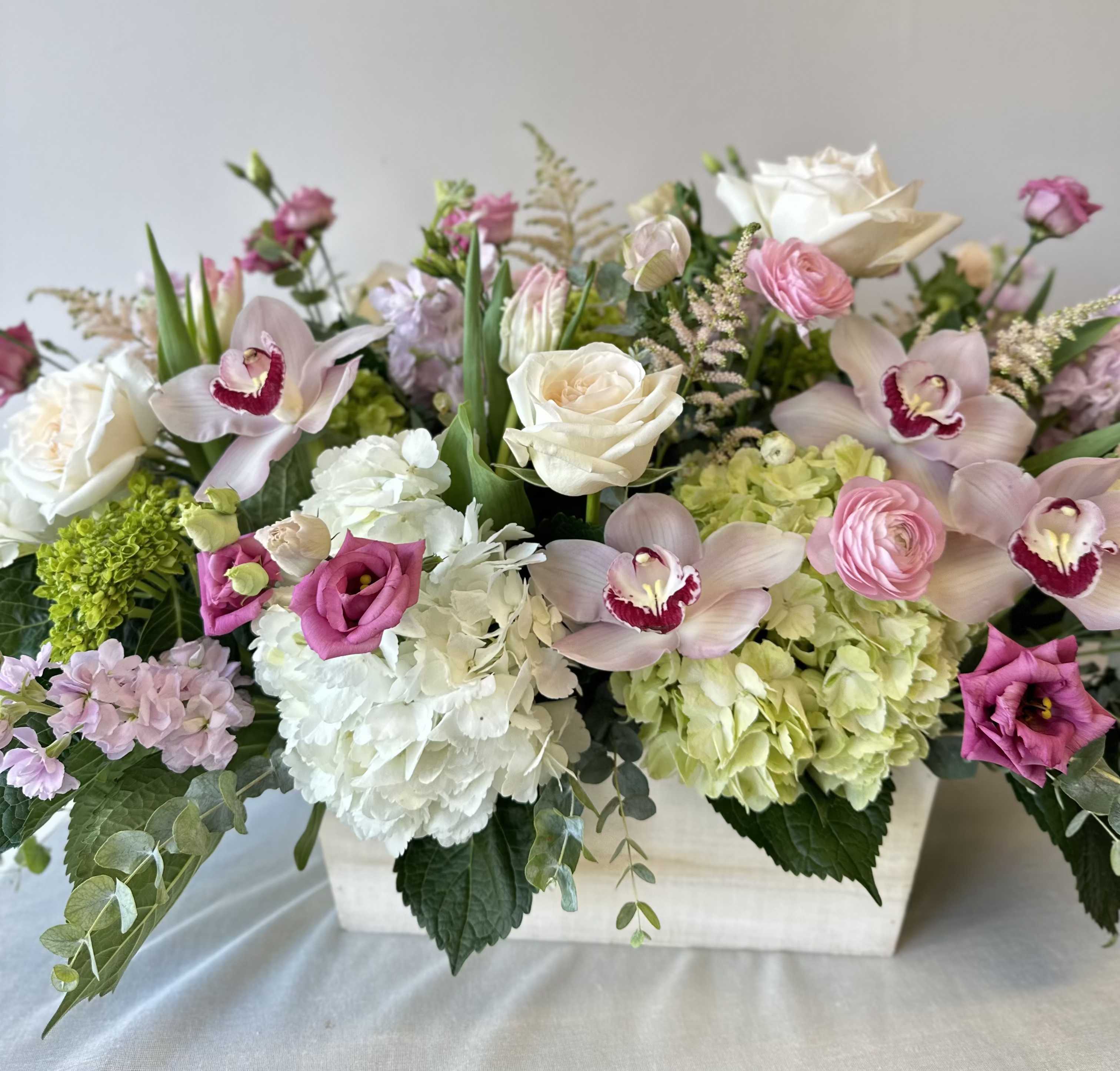 Beyond Beautiful - An extravagant arrangement of dazzling flowers in a large oblong planter box. Hydrangea, lisianthus, garden roses, orchids, ranunculus, veronica, eucalyptus, and other sensational seasonal stems.