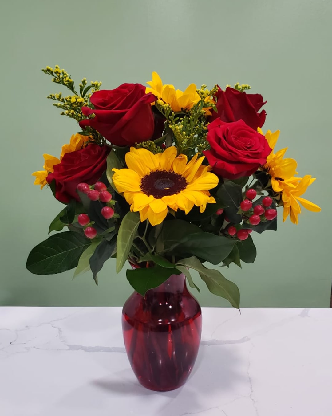 Love Everyday - This stunning arrangement as sunflowers, red roses, solidago and hypericums in a red ginger vase. 