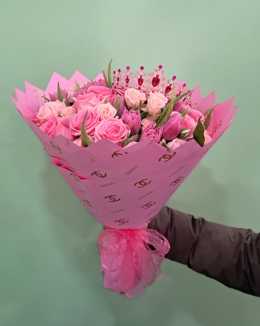 Pink Diamonds - This sparkling and fun bouquet has pink roses, tulips, and light pink spray roses all wrapped in pink waterproof paper and adorned with a pink crown. 