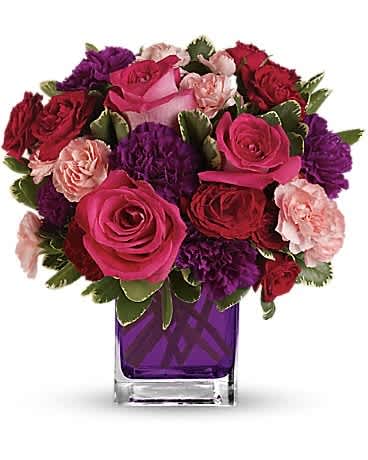 Bejeweled Beauty - Pure romance. Hot pink roses and dark red spray roses are brightly arranged inside our violet cube. Please note, substitutions with the cube vase may take place. We will replace with the most similar vase we are able to. Hot pink roses, dark red spray roses, purple carnations and pink miniature carnations are accented with assorted greens. Delivered in Teleflora's glass violet cube.