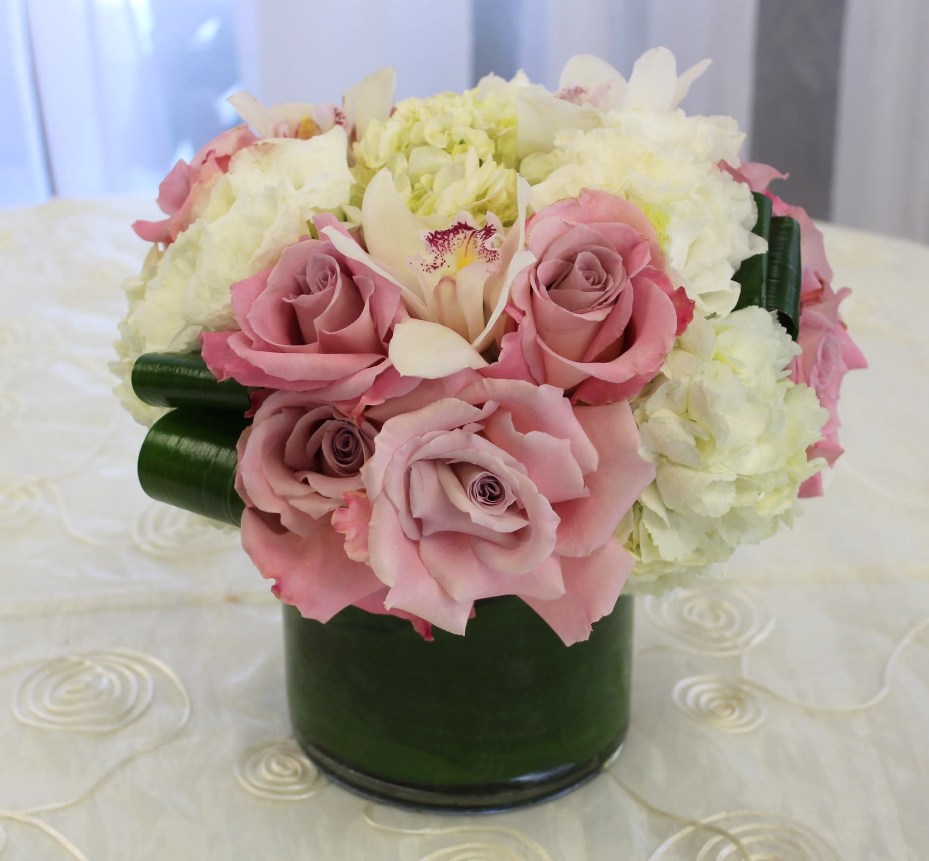 Pave Roses and Hydrangeas - Pave bouquet with roses, hydrangeas and cymbidium orchids in a cylinder vase. 