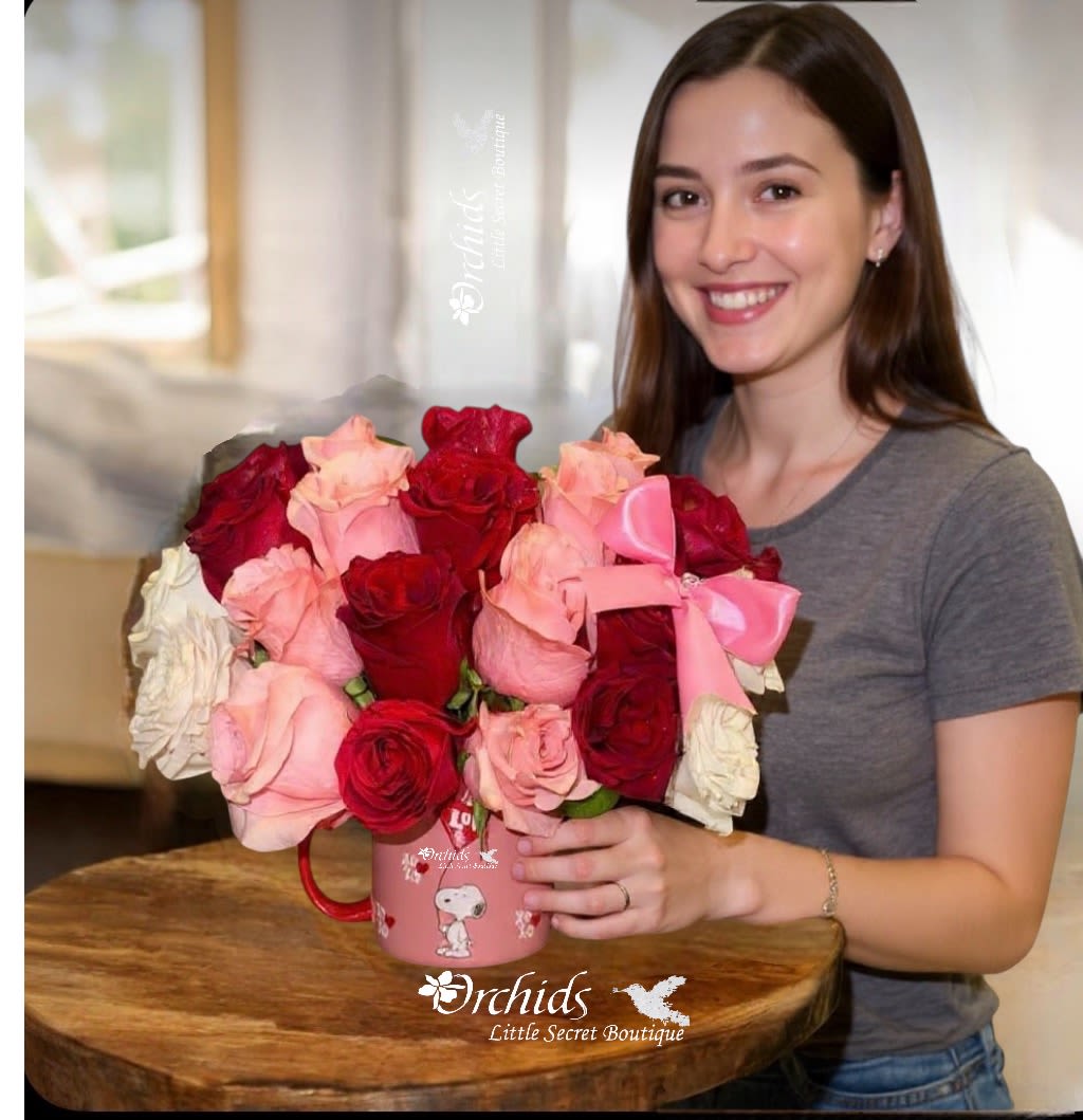 Soft Pink Red White Roses  Snoopy LUV XOXO Mug Arrangement  - Arrangement measures approximately 12”H A vibrant assortment of fresh-cut Premium roses in deep red, soft pink, and white hues, artfully arranged within a charming light pink ceramic mug. The mug features a Snoopy graphic with "XO" (hugs and kisses) text and "Luv," complemented by a red handle, adding a whimsical touch. A bright pink satin bow, positioned on the corner of the bouquet, enhances its festive appeal. This romantic floral arrangement is ideal for Valentine's Day, anniversaries, or any occasion requiring a touch of sweetness.
