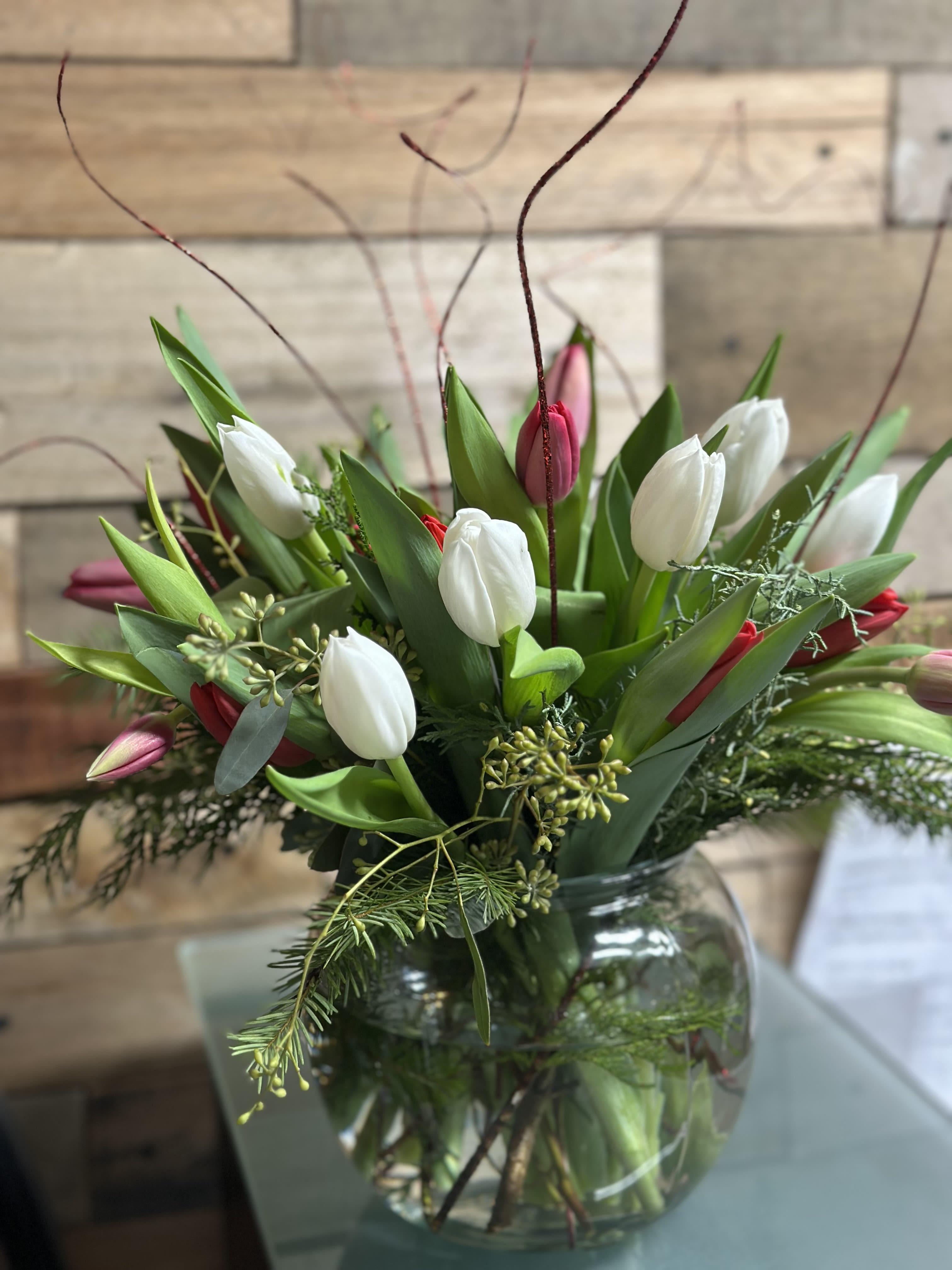 Burst of Tulip - Grace in Every Stem of these lovely tulips as they strout through a lush mix of greenery. Valentine accents give the final touches to this beautiful bloom.