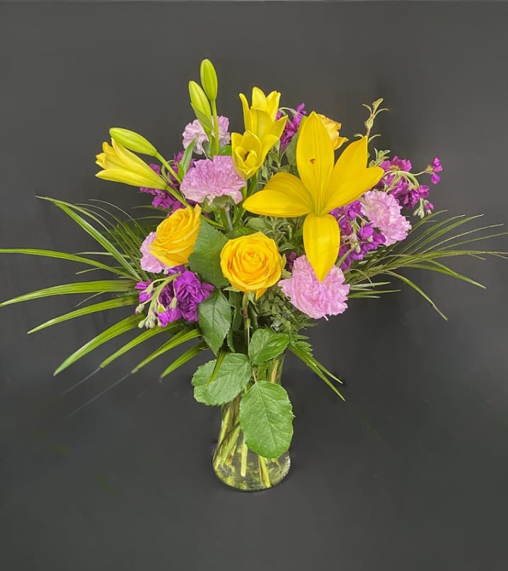 Stellar Yellow - With beautiful golden yellow and deep purple tones, this flower arrangement is sure to impress! Perfect for almost any occasion, this stunning bouquet is filled with yellow roses, purple stock, yellow Asiatic lilies, lavender carnations, and beautiful greens. Add a pop of color to any room and order Stellar Yellow today!