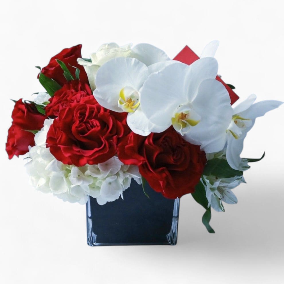 Love Ya Bouquet Designer's Choice - Red and white blossom selection of that day roses orchids and more arranged in a modern glass cube vase. Perfect for every occasion. Send this beautiful bouquet today to show them how much you love them. All fresh flower designs that leave my flower studio shop are beautiful works of art, made special each and every time. Send them your love! Send them a special bouquet to make them smile.